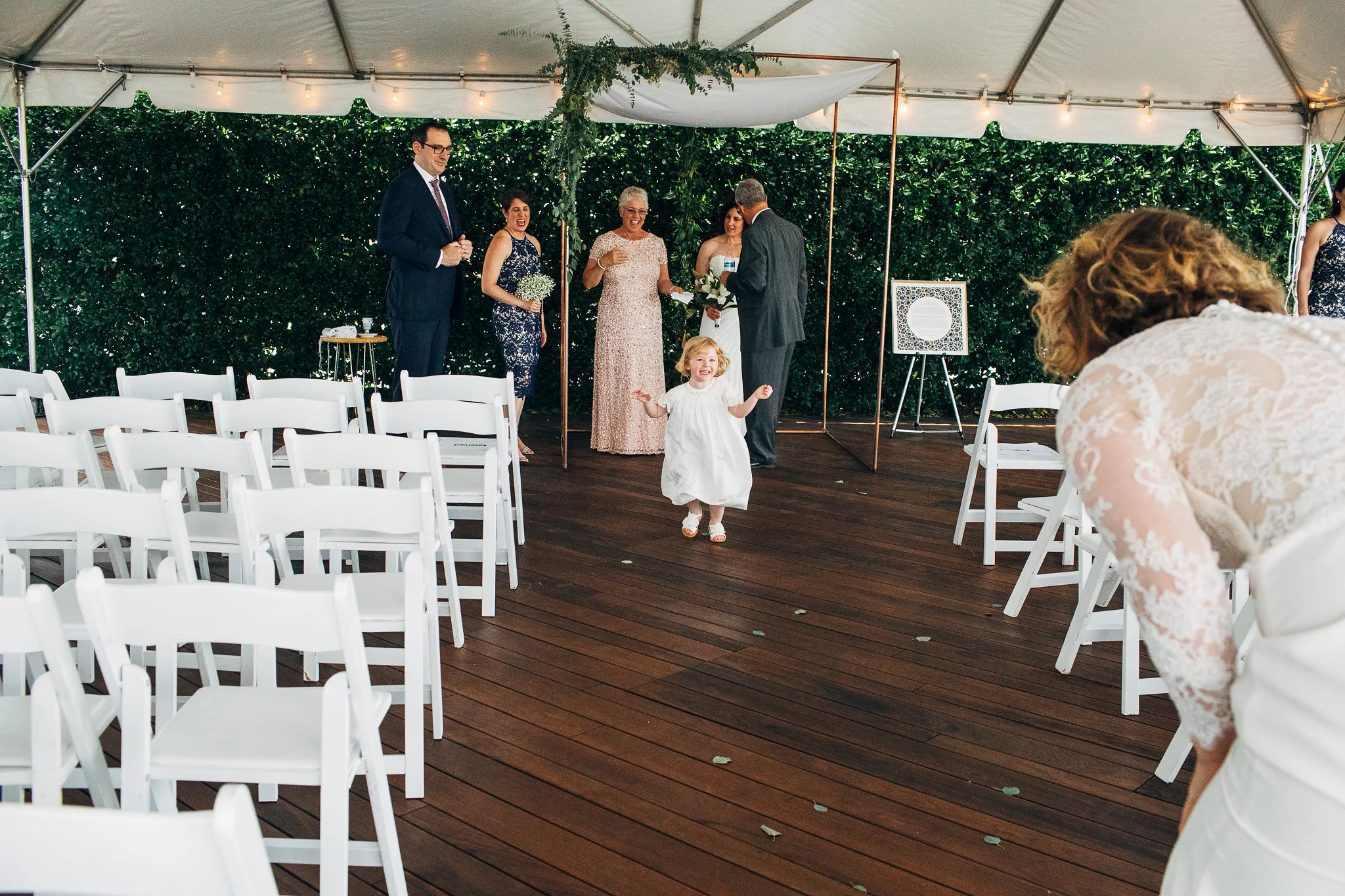 Bride at altar visiting with guests, while young girl runs down the aisle to her mother