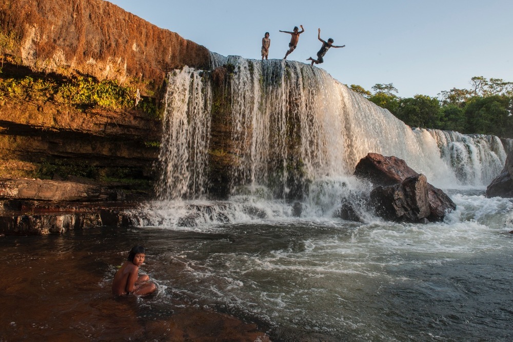 CHILDREN OF THE KAYAPO TRIBE LEAP OFF A WATERFALL. PHOTO: CRISTINA MITTERMEIER