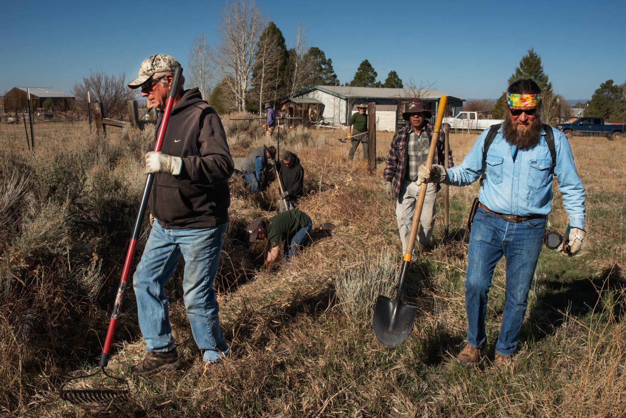   Local members of Rio Lucero y Arroyo Seco Acequia Association work together in the annual spring-time clearing effort. President Brian Duran is seen on the right with shovel in hand.  