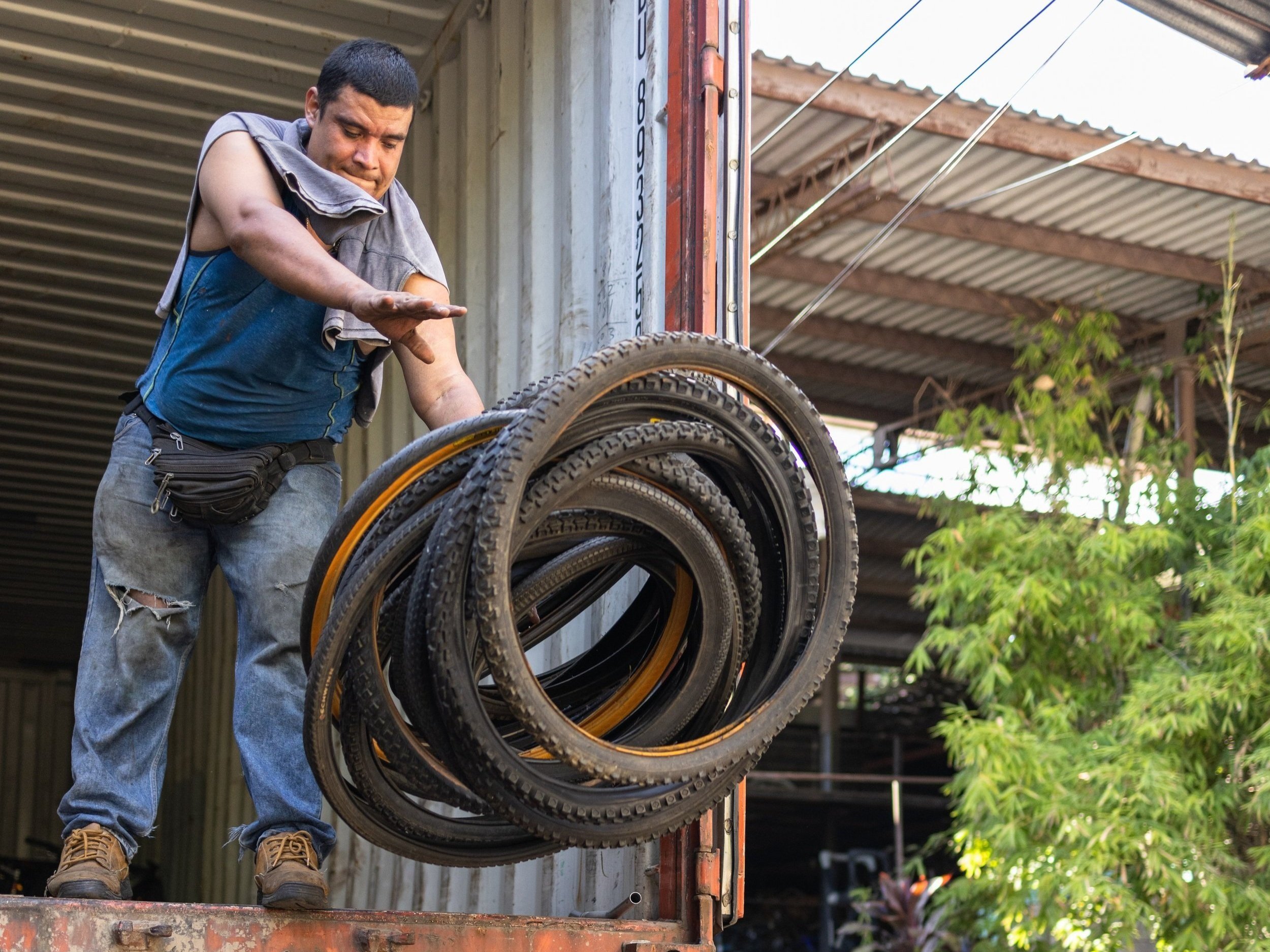  Heriberto Reyes Cortez tossing bike tires from the back of a container truck at CESTA. 