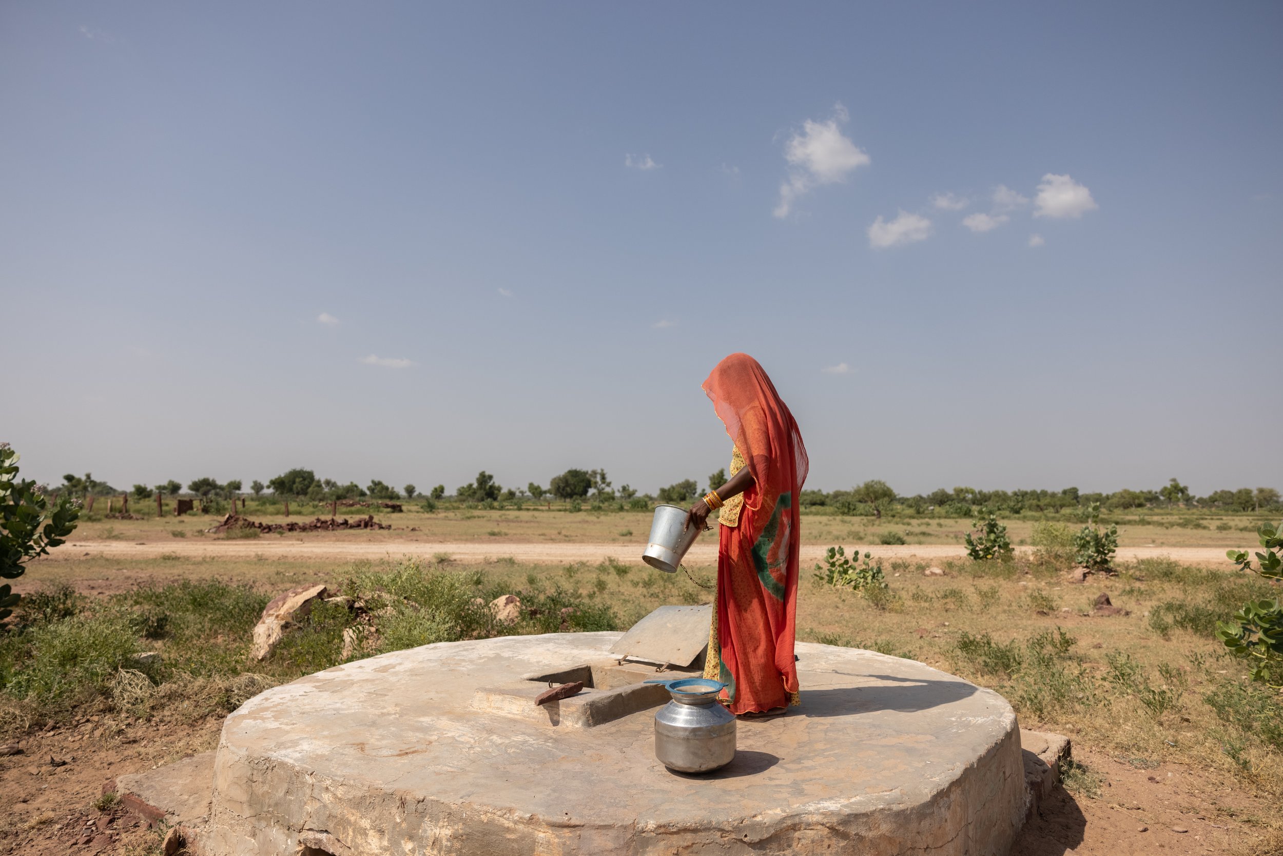 Mirgo collecting water from the rainwater harvesting tank outside her home.