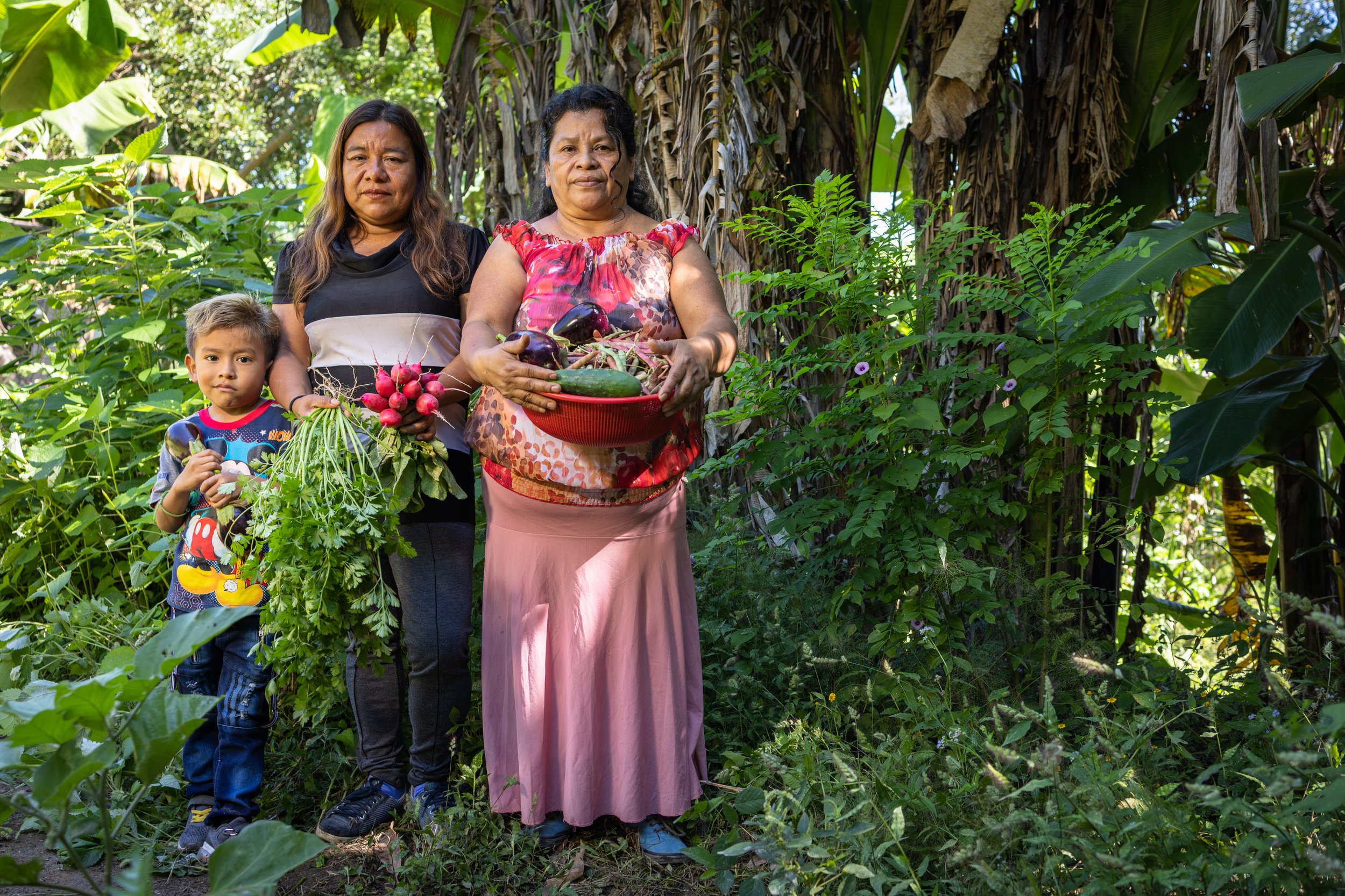 Two women cooperative members pose with their harvest and boy.