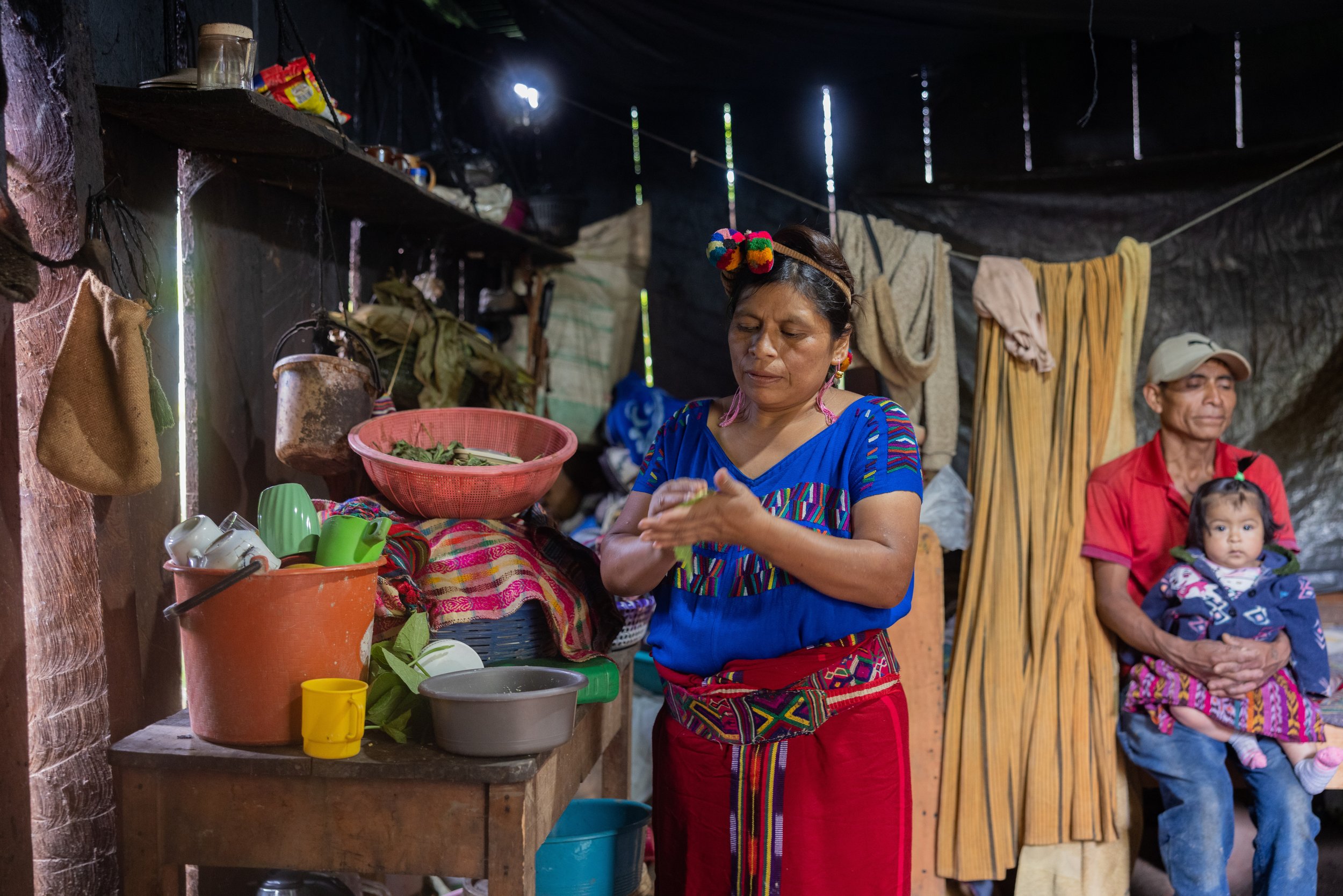 Cristina’s mom makes boxboles while her husband holds their daughter. He works in agriculture 6 days a week but can only work 5 hours per day due to the 2-hour commute (each way) to the farms on foot.