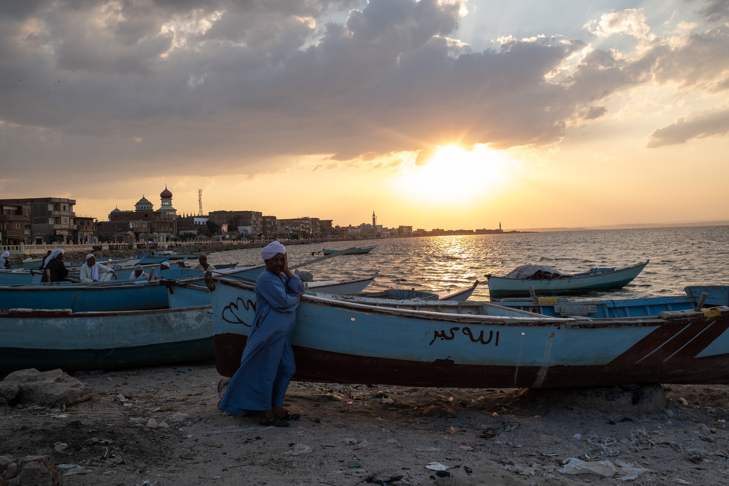 Fishermen stand next to their boats along the shore of Lake Qarun in Ezbat Soliman village.