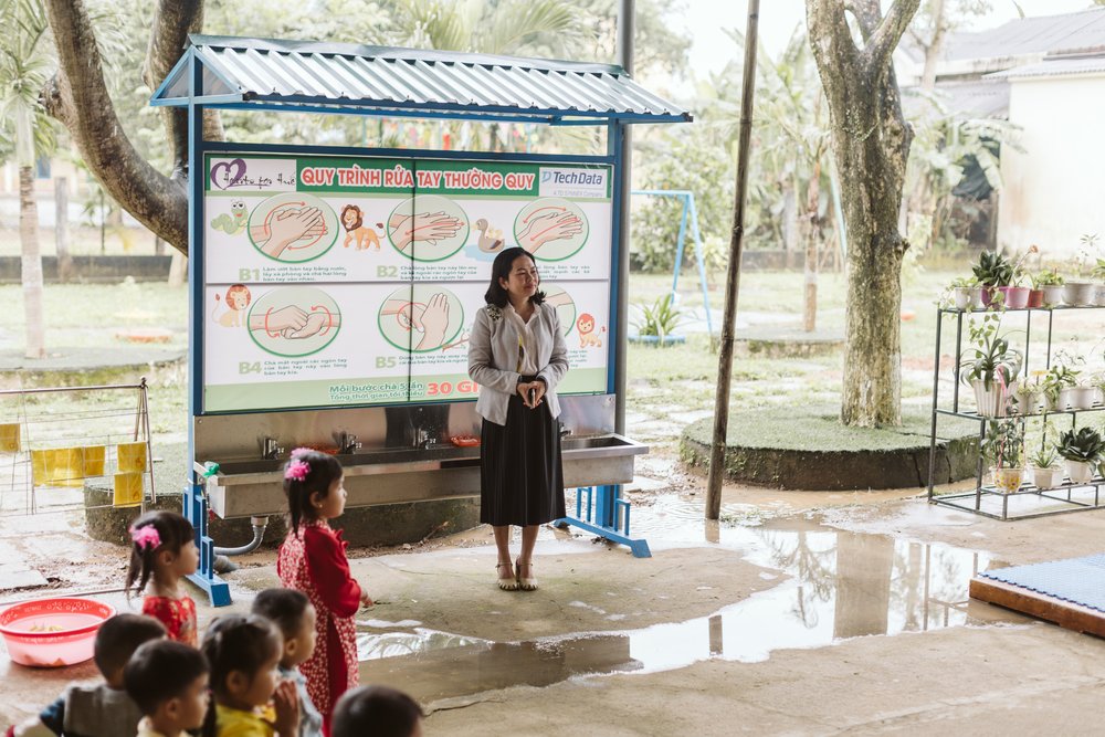 A teacher stands in front of the handwashing station at Tay Xuan kindergarten.