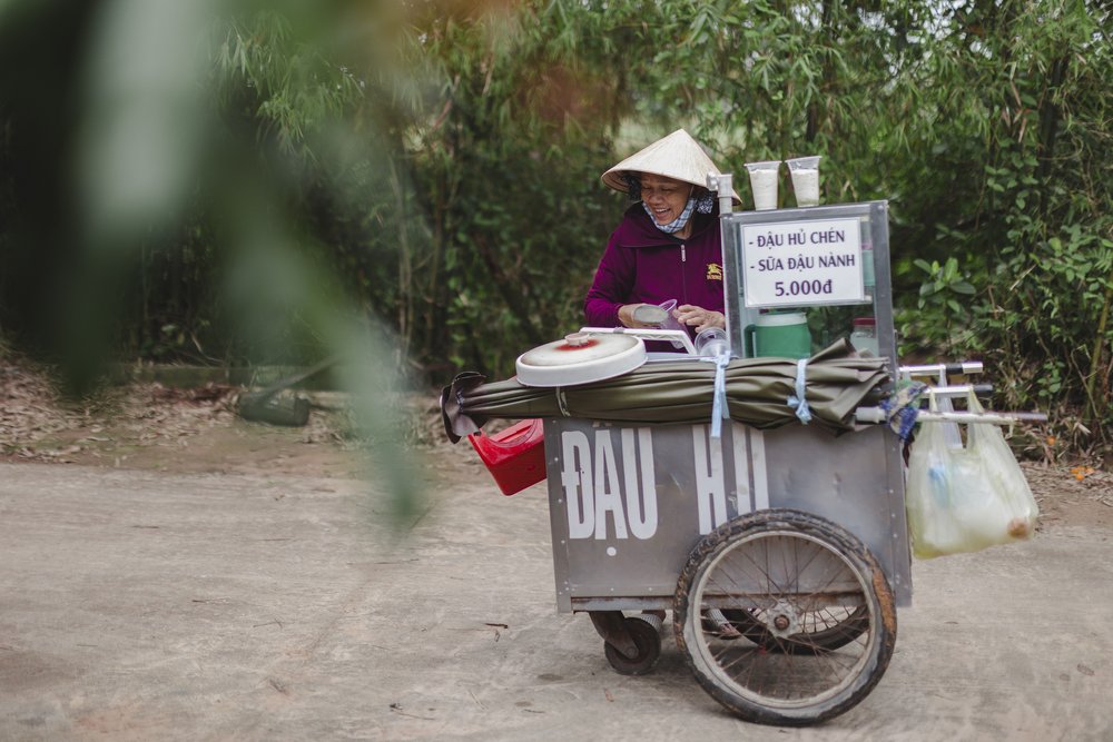 Ms. Cuc still works long days, walking at least 3 kms on gravel roads pushing her cart to sell tofu and tea at the market to make ends meet.