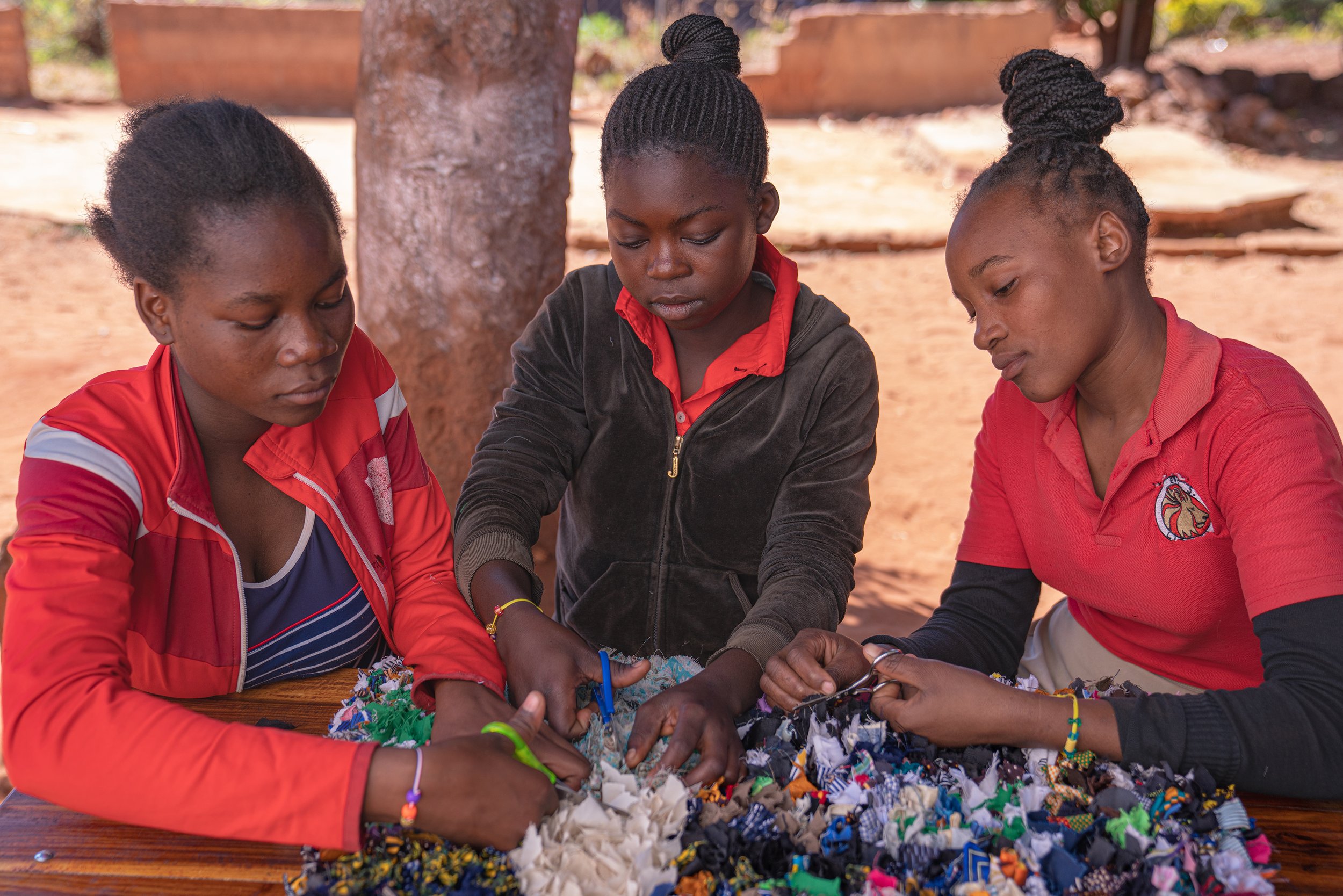  Students working on  craft of hooked carpet using salvaged fabrics. 