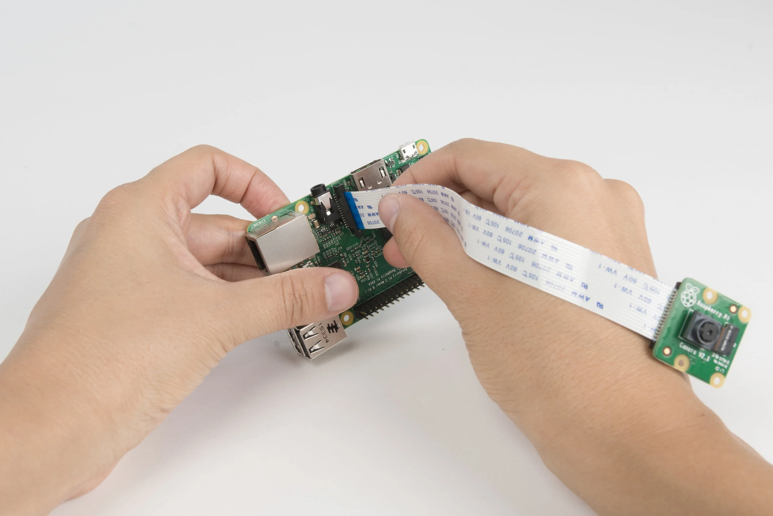 Step 5 Connect camera module to the Raspberry Pi. Make sure to match the direction of the camera to the picture. The printed side of the ribbon should face towards the USB ports of the shield.