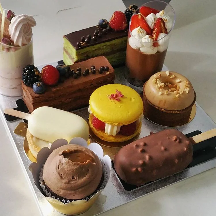 rom left to right: coconut strawberry mousse, pistachio opera, gluten free chocolate roulade, dark chocolate cheesecake, wild strawberry tart, raspberry macaron, praline tart, salted caramel cupcake and caramel hazelnut entremet