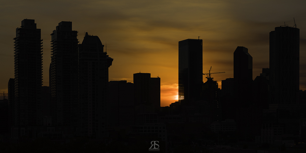 Expose for the brightest part of the image. In this case the sky closest to the sun. This will render a silhouette of the city skyline. Note a point of interest being the sun shinning through the empty floors of Brookfield Place.
