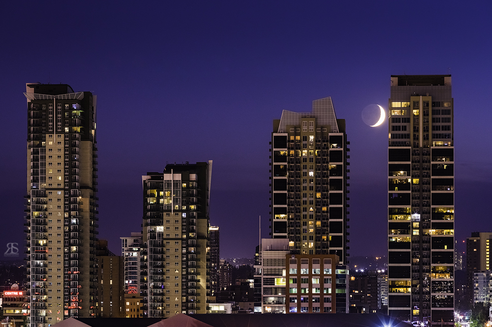 From the same location I noticed the moon was setting. I waited until the moon sank between the two buildings. I should've set up faster to centre the moon between the structures but by the time I took the picture the moon had moved rather quickly. Be prepared!