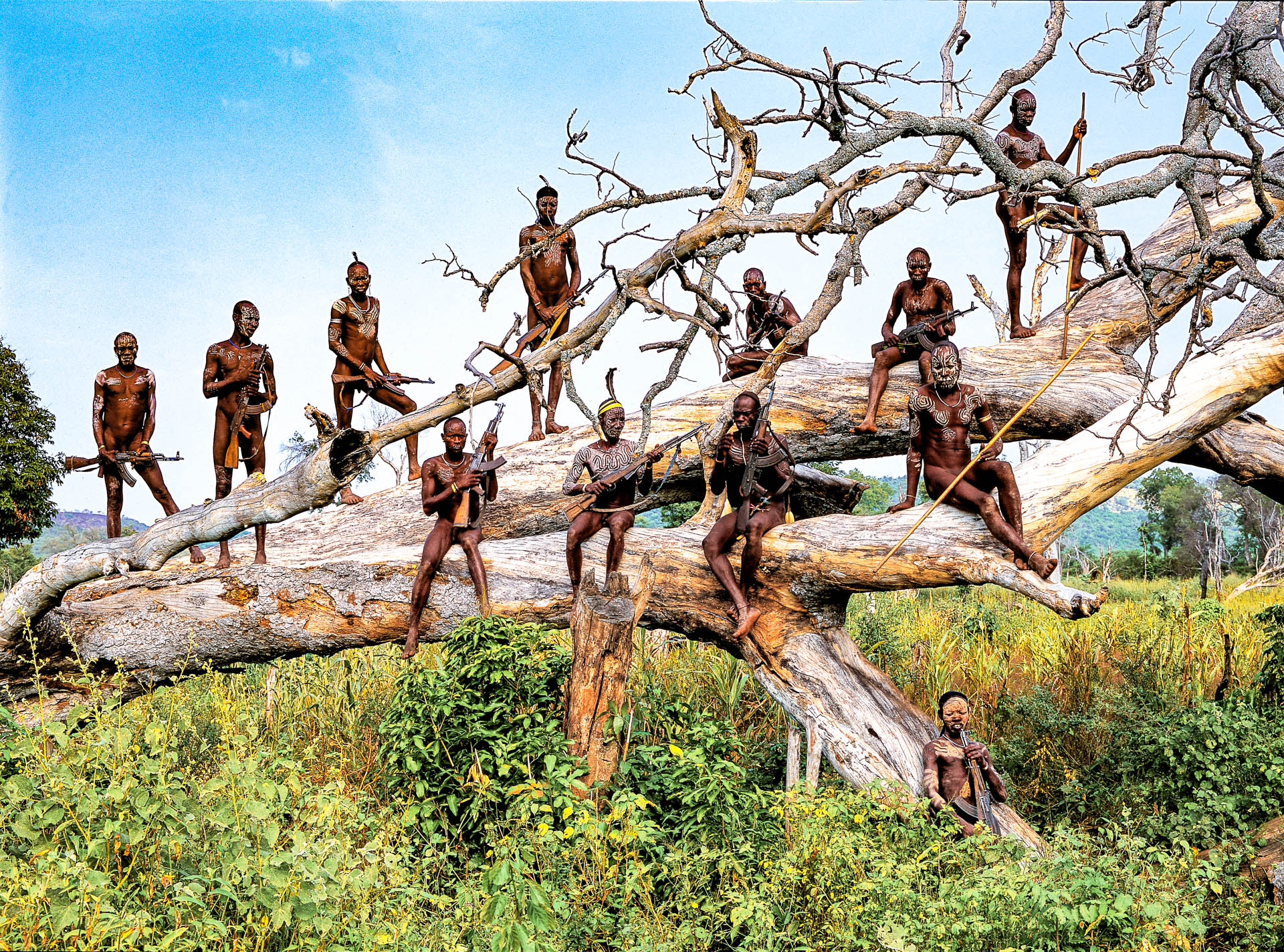  A group of warriors  armed with Kalashnikovs on a huge tree at the edge of the village of Komba. 