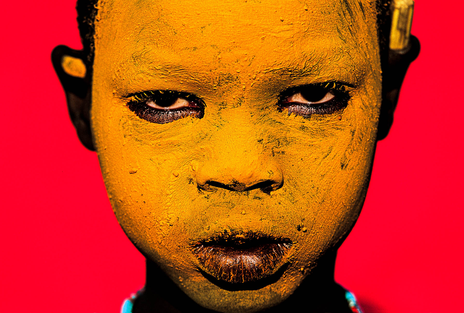 A Surma child, whose face is painted yellow, poses for the photographer.