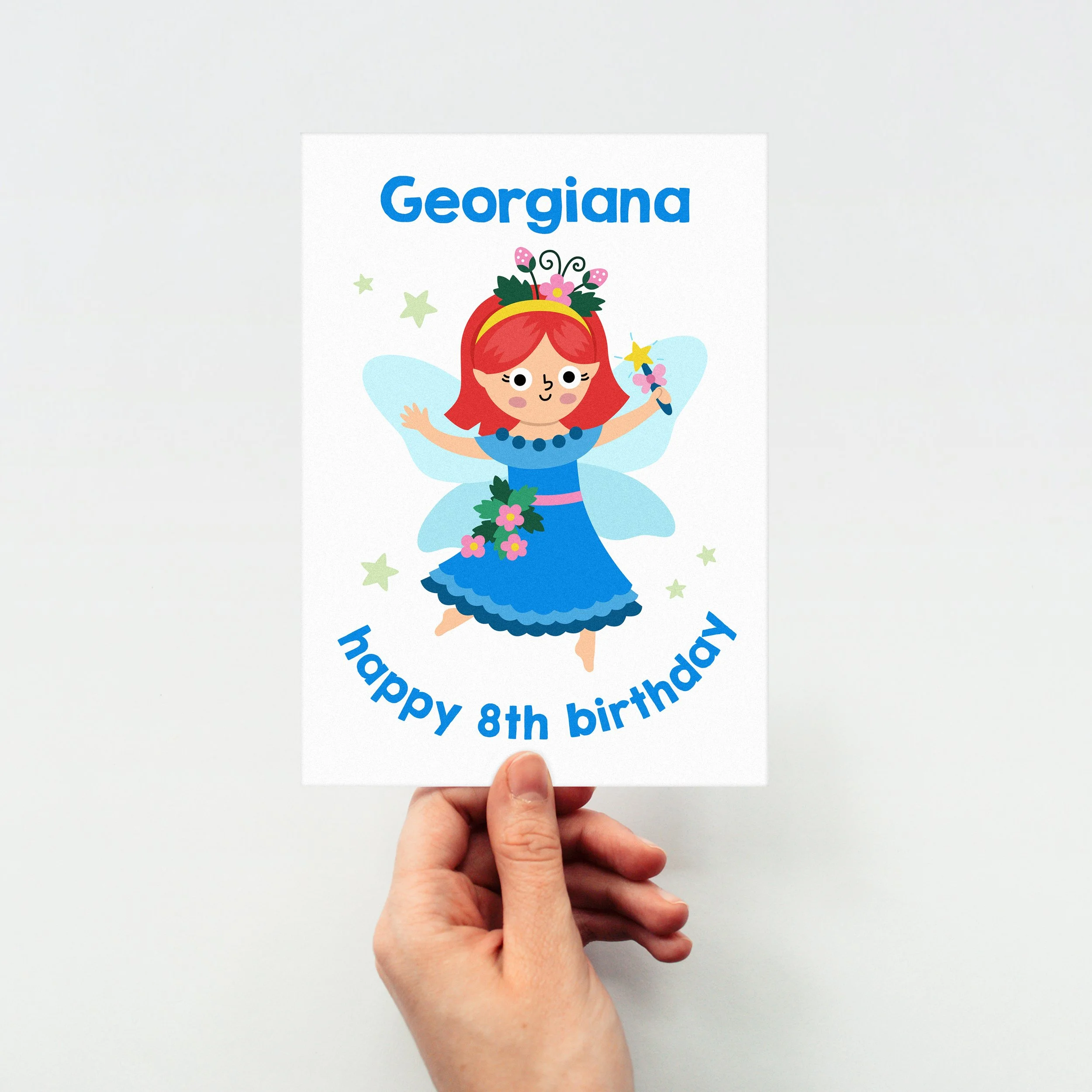 Hand holds a cute birthday card personalised with a girls name and age for her birthday - features an illustration of a flower fairy princess in shades of blue