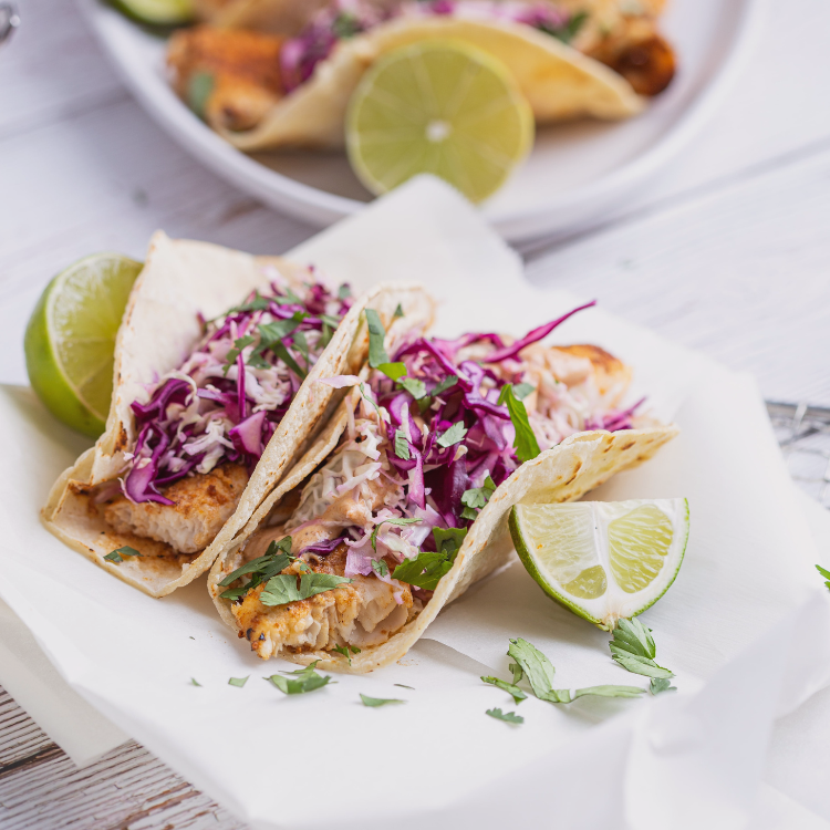 Fresh fish tacos with shredded purple cabbage slaw and lime wedges – high-protein, low-calorie whole food recipe.