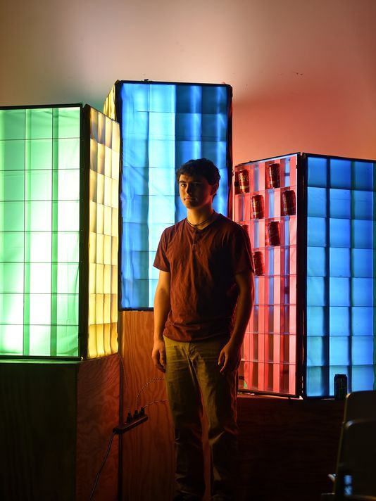 Zachary White, architect student at Mississippi State University. Standing in front of one of his light pieces. The piece is called 'pop light' & was inspired by Andy Warhol's pop art.