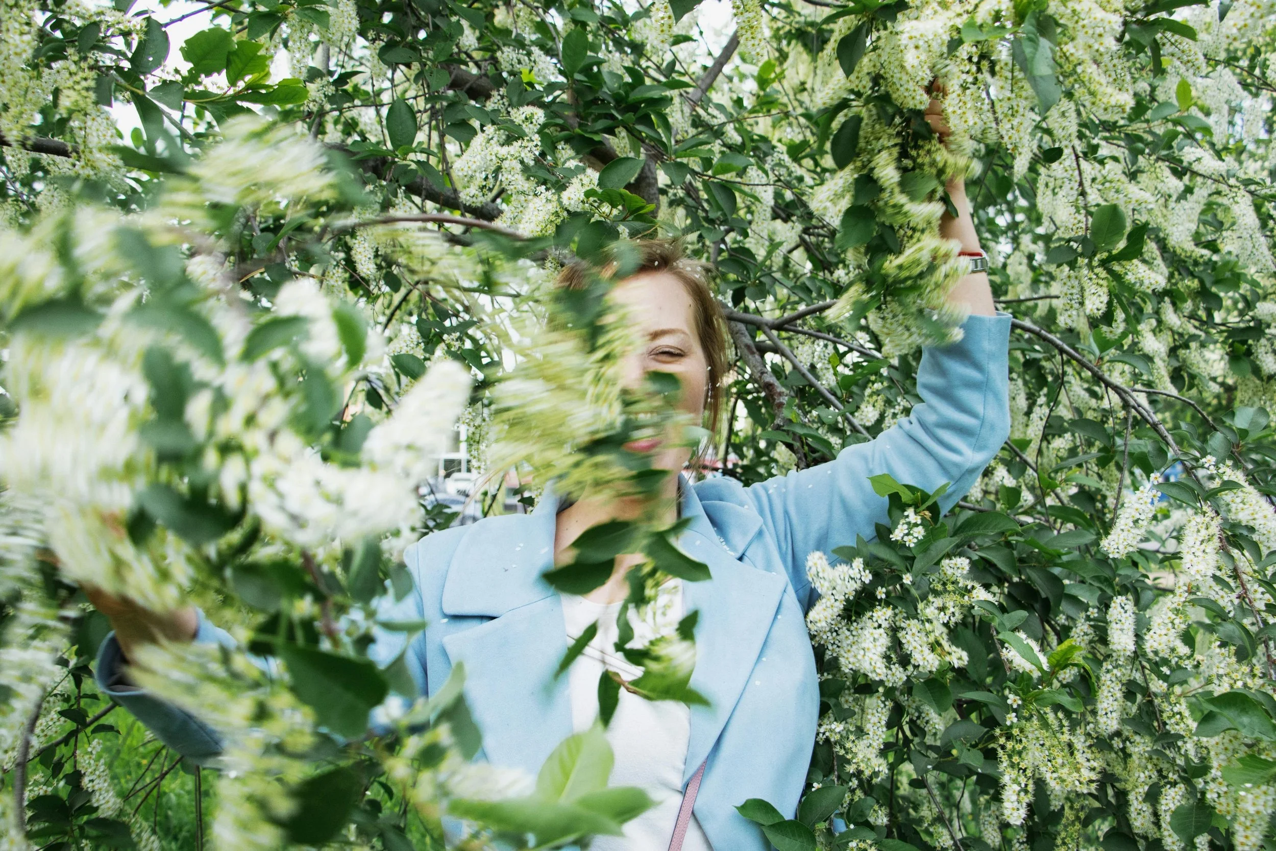 Woman in a blazer playing behind leaves