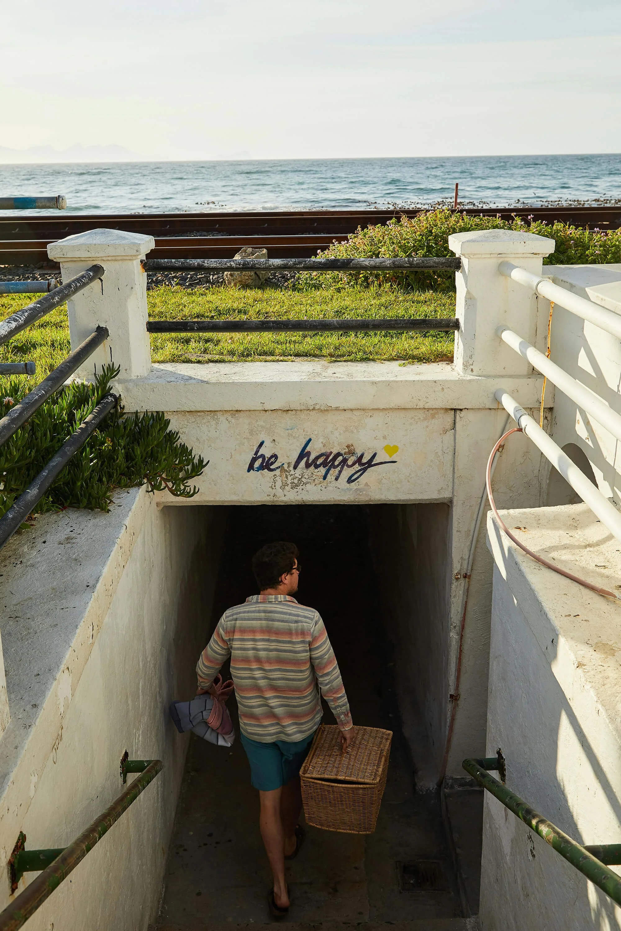 Man carrying a basket under a sign that says be happy