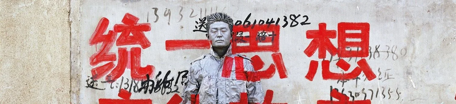 Liu Bolin camouflaged against a wall in his signature photographic practice