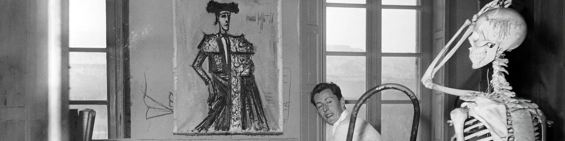 Bernard Buffet in his studio beside a drawing and a human skeleton