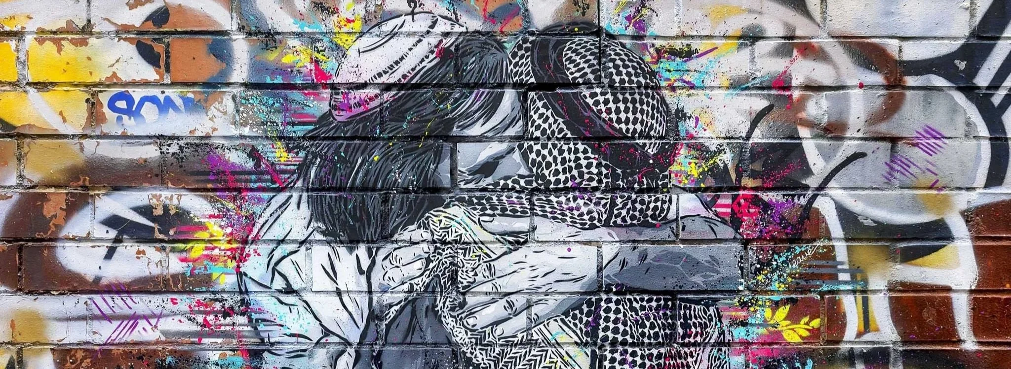 Stencil artwork by VALÉ depicting two figures against a colorful urban background