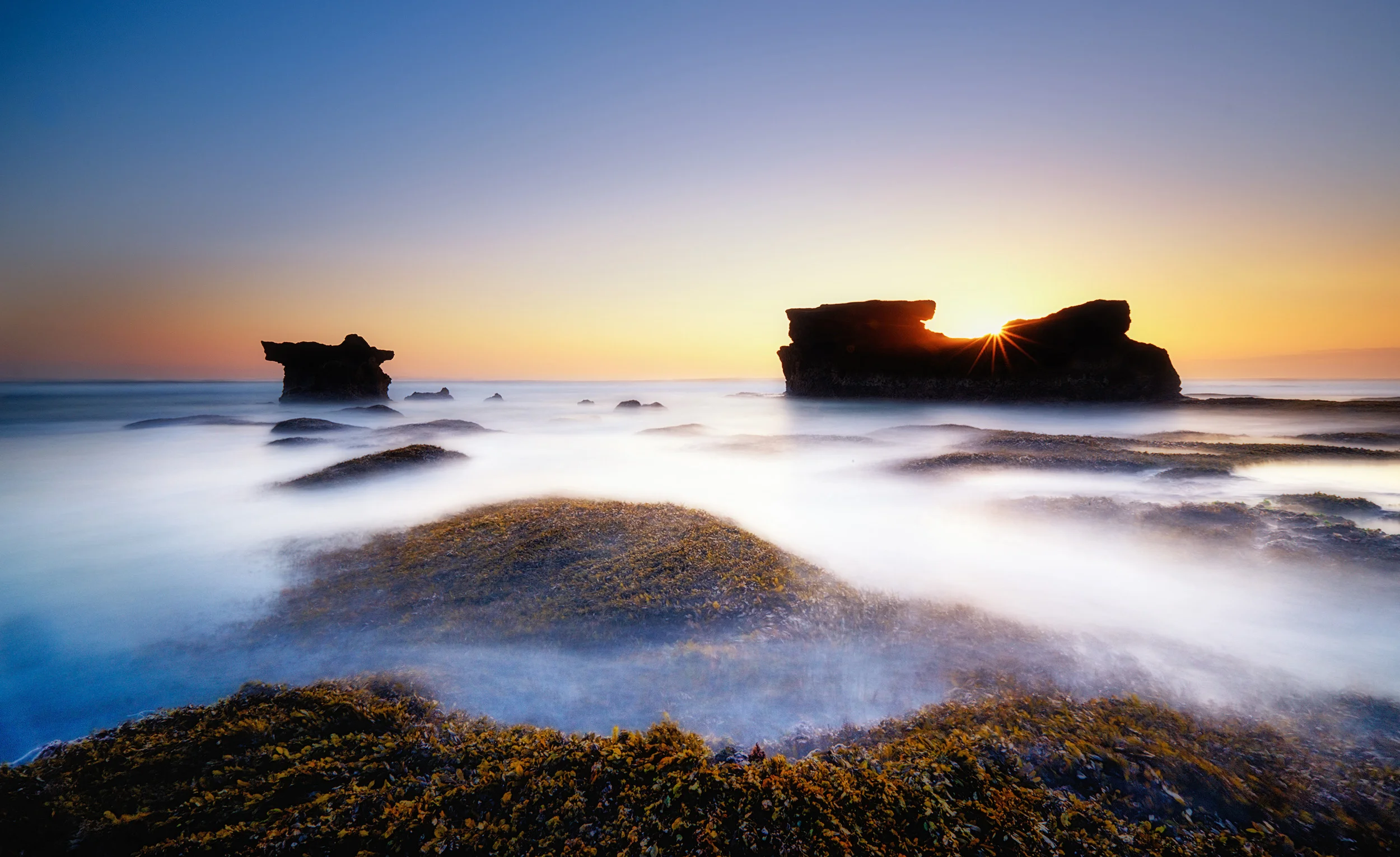 Bali Coast The southern Bali coast at sunset. We headed to the coast to shoot one of the beaches next to Tanah Lot but the tide made it impossible to access so we walked away from the temple, crossing several beaches until I found this location to photograph. I was hoping for a more interesting sky, but at least the light was wonderful. I used Lee filters to to control the brightness of the sky and lengthen the exposure time.