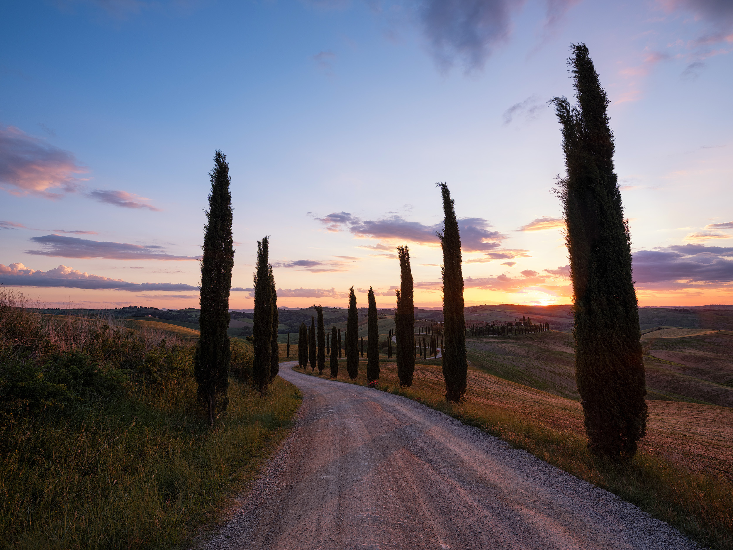 Baccaleno A winding, cypress lined road across rolling hills to a stone farmhouse. It can only be Tuscany. This image was taken in Crete Senesi, south of Siena.