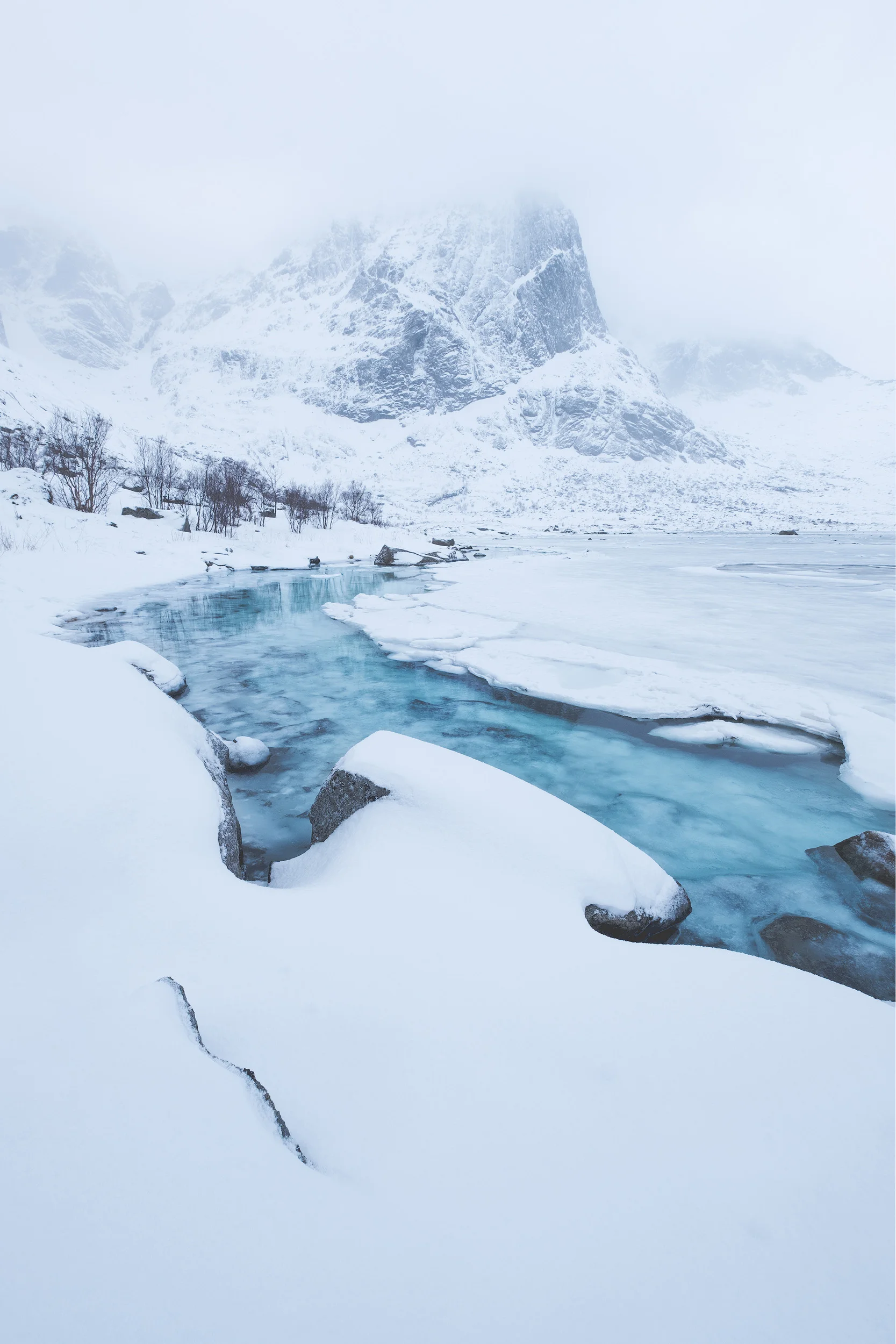 White & Blue The clear blue water of an almost frozen fjord surrounded by the a fresh snowfall in the Lofoten Islands, Norway