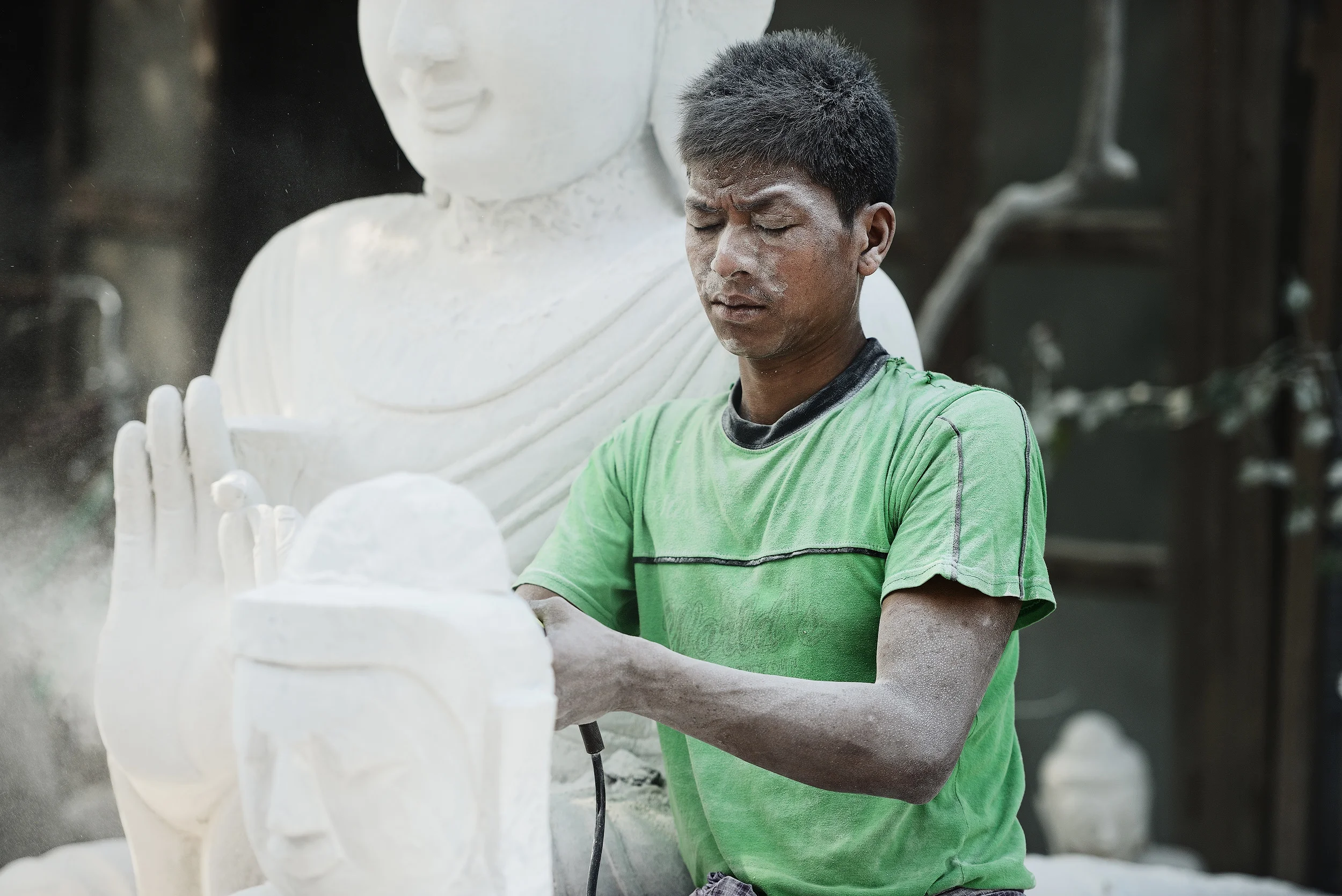 The Stone Carver Scattered at roadsides throughout Amarapura and Mandalay are lots of stone carvers who shape and carve slabs of stone into buddhas of all shapes and sizes. Watching the carvers work on buddhas in various states of completion is a fascinating process as they hone the statues into their finished forms. It’s brutal work and after just a few minutes standing watching you’ll feel the dust in your eyes and throat and yet the men here work without goggles or masks breathing the dust all day long, day after day.
