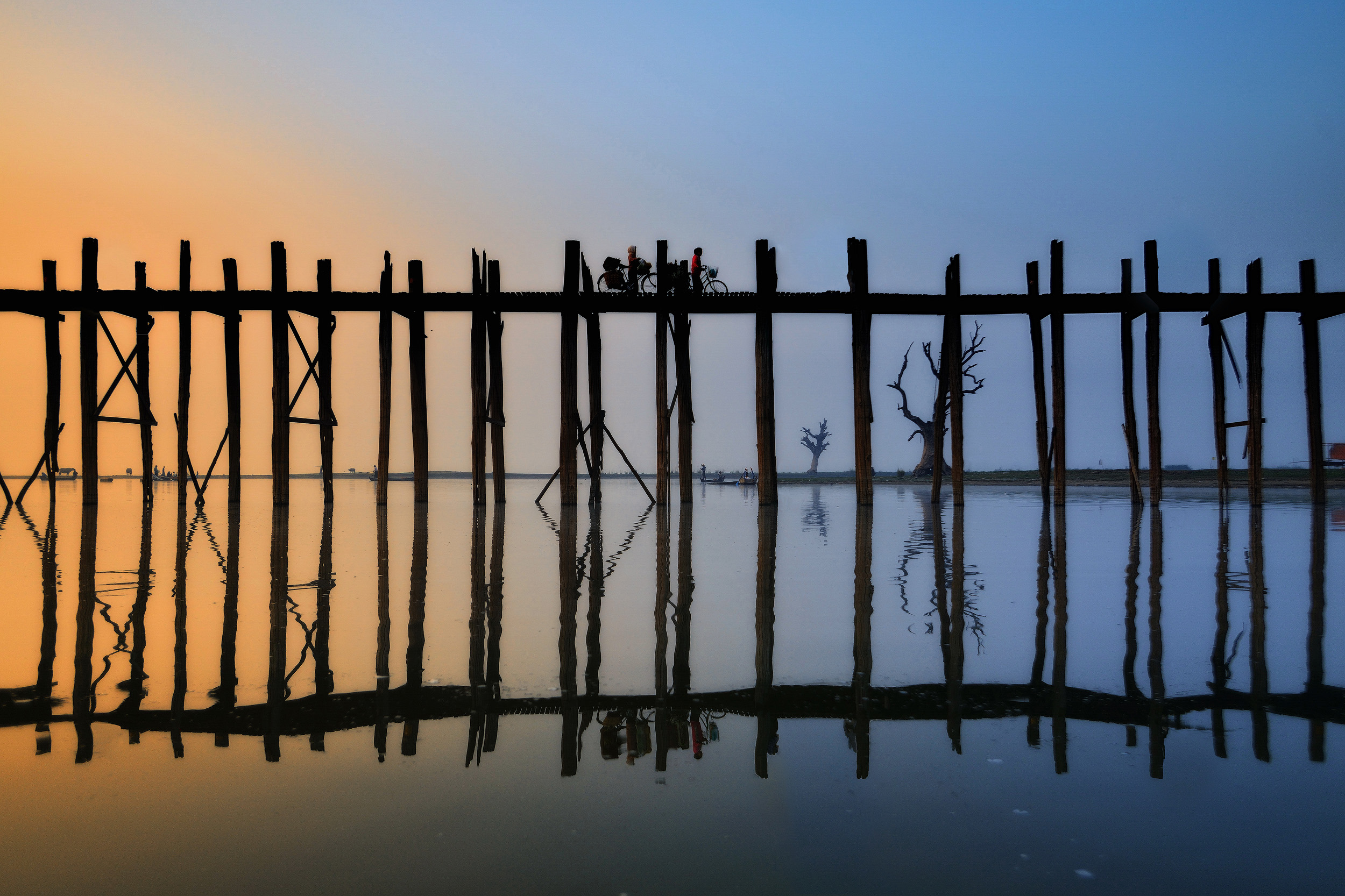 U Bein Reflection U Bein bridge in Amarapura, southern Mandalay, as the sun burns through the mist at dawn. I set off in a boat when it was still dark and misty and photographed the bridge as it got busier and busier with early morning commuters.