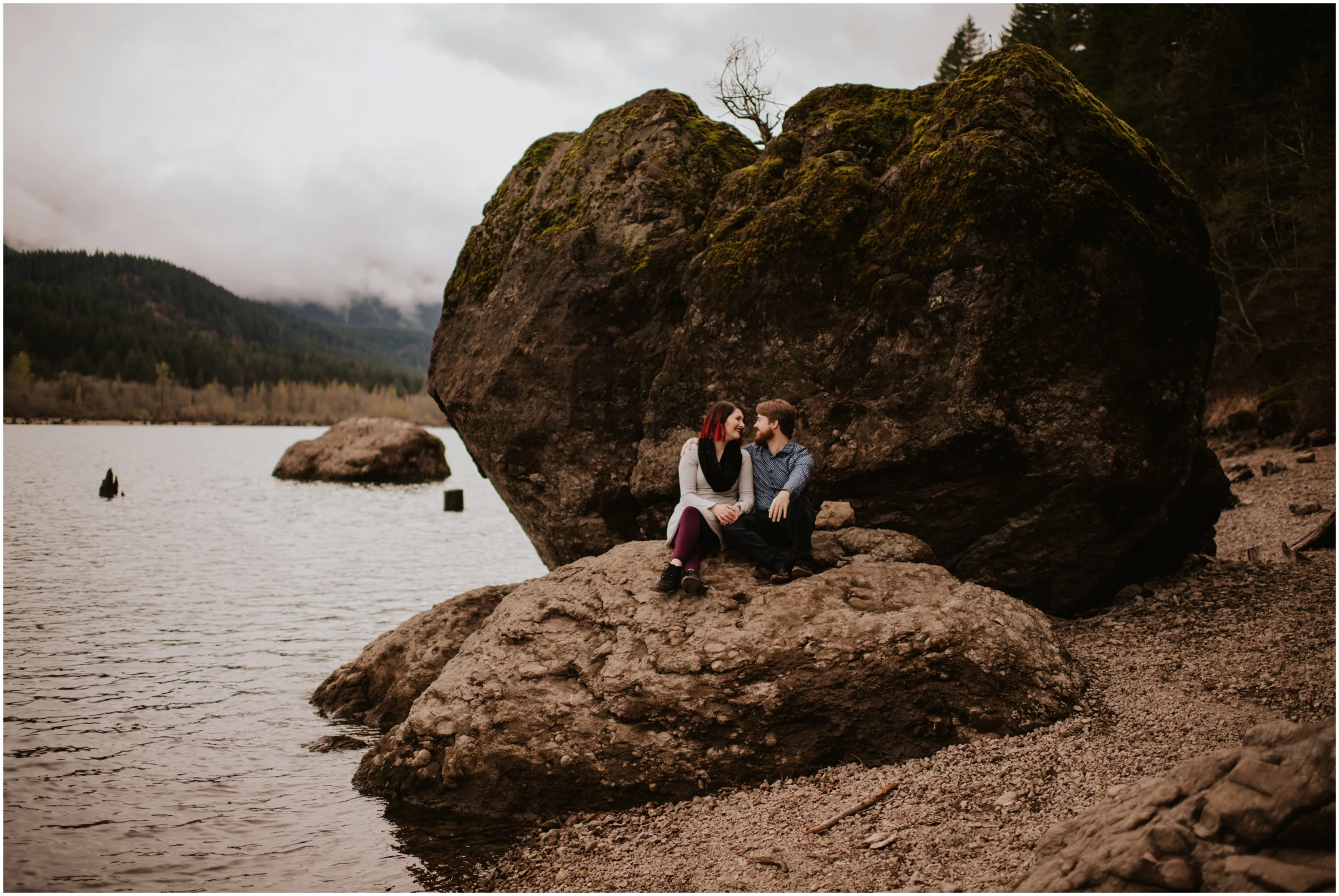 couple cuddling on the rocks at Rattlesnake Lake, WA | Seattle Wedding Photographer www.riversandroadsphotography.com