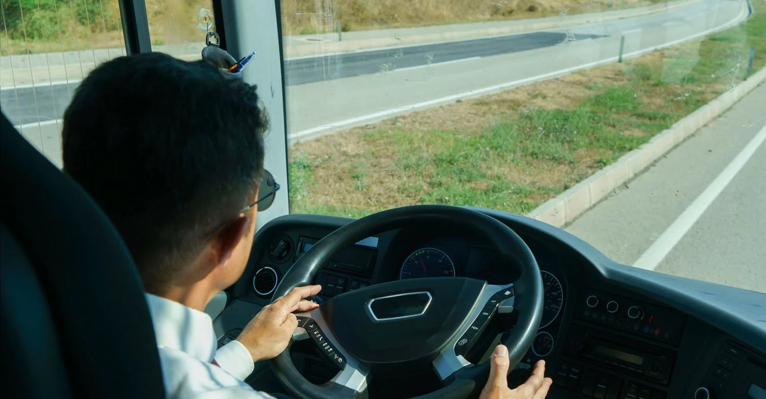 Professional motorcoach driver behind the wheel on a highway.jpg