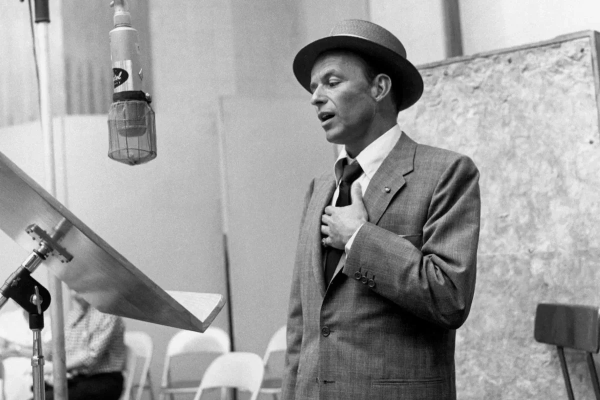Frank Sinatra recording in a studio with a vintage valve microphone.