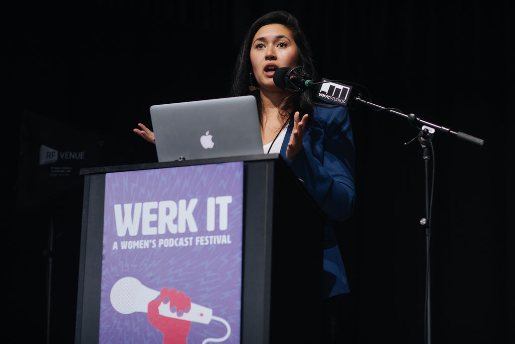 Megan Tan presenting on stage behind a podium