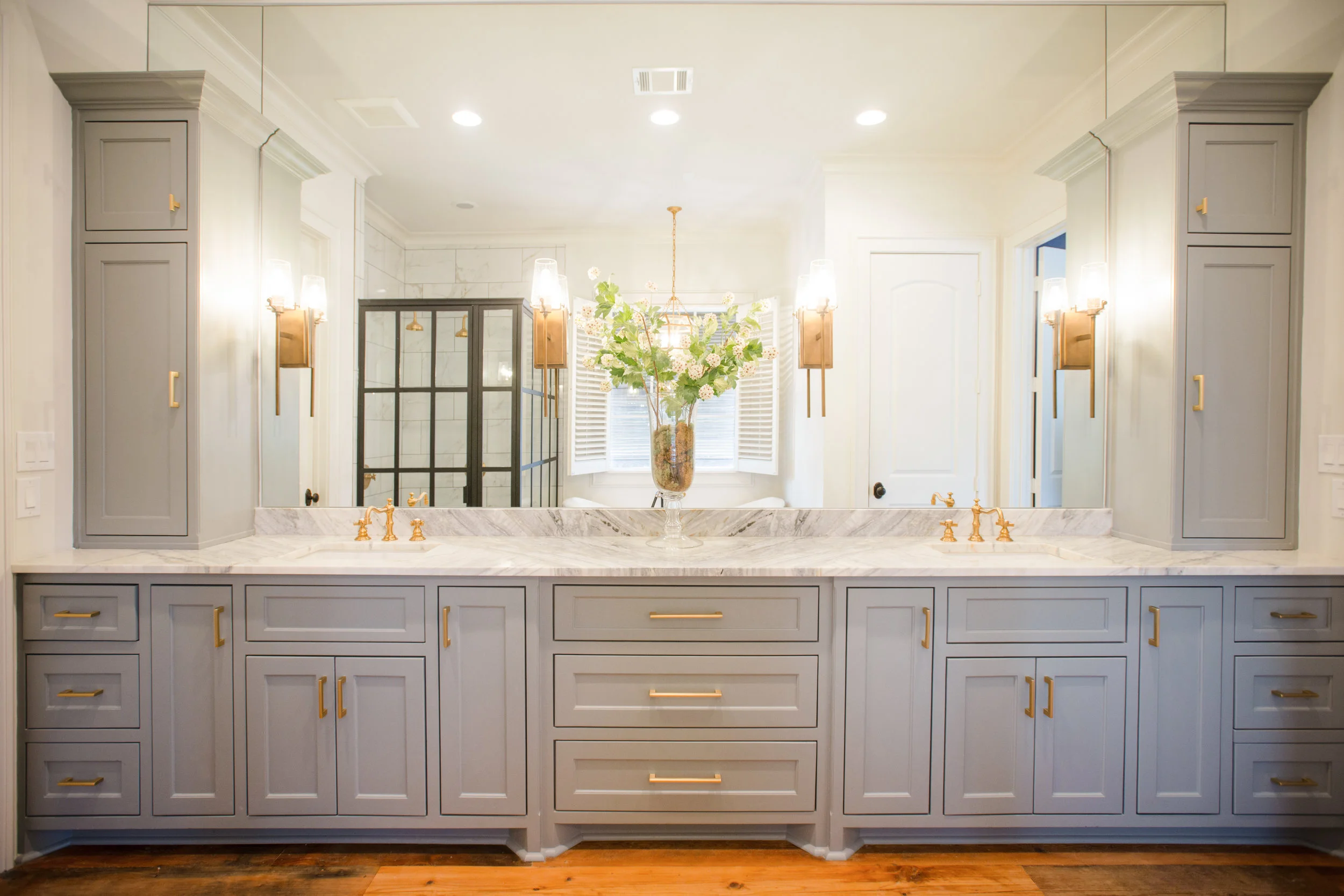 We used a beautiful grey on the cabinets that really compliments the gorgeous super calcatta slab on top. Brushed gold faucets, sconces and hardware. 