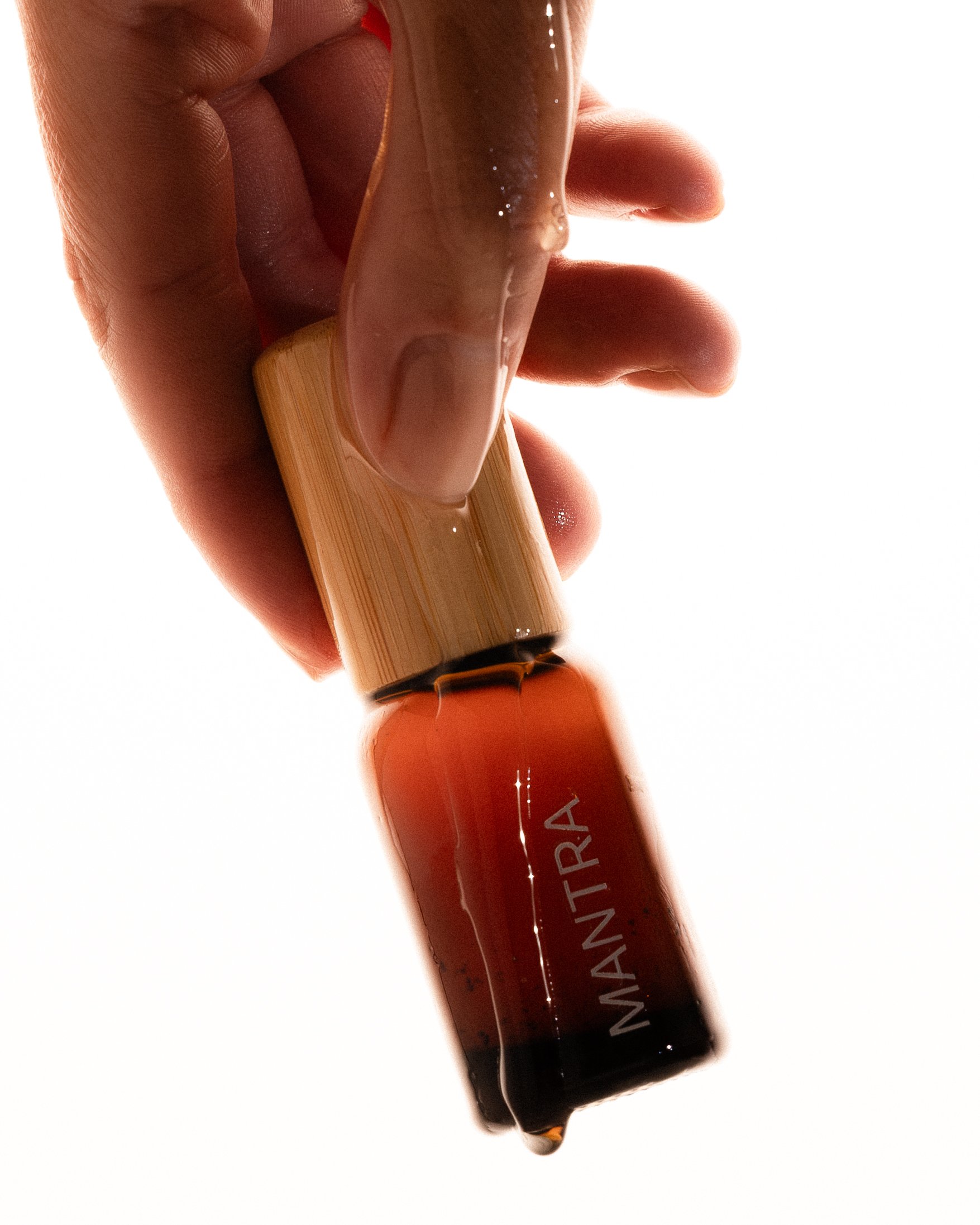 Close-up of a hand holding a lip gloss tube with the cap removal showing gloss at the opening.