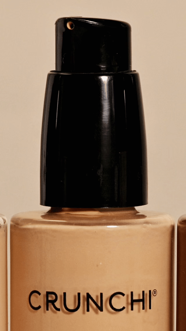 Close-up of a bottle of CRUNCHI liquid foundation with a black pump dispenser.