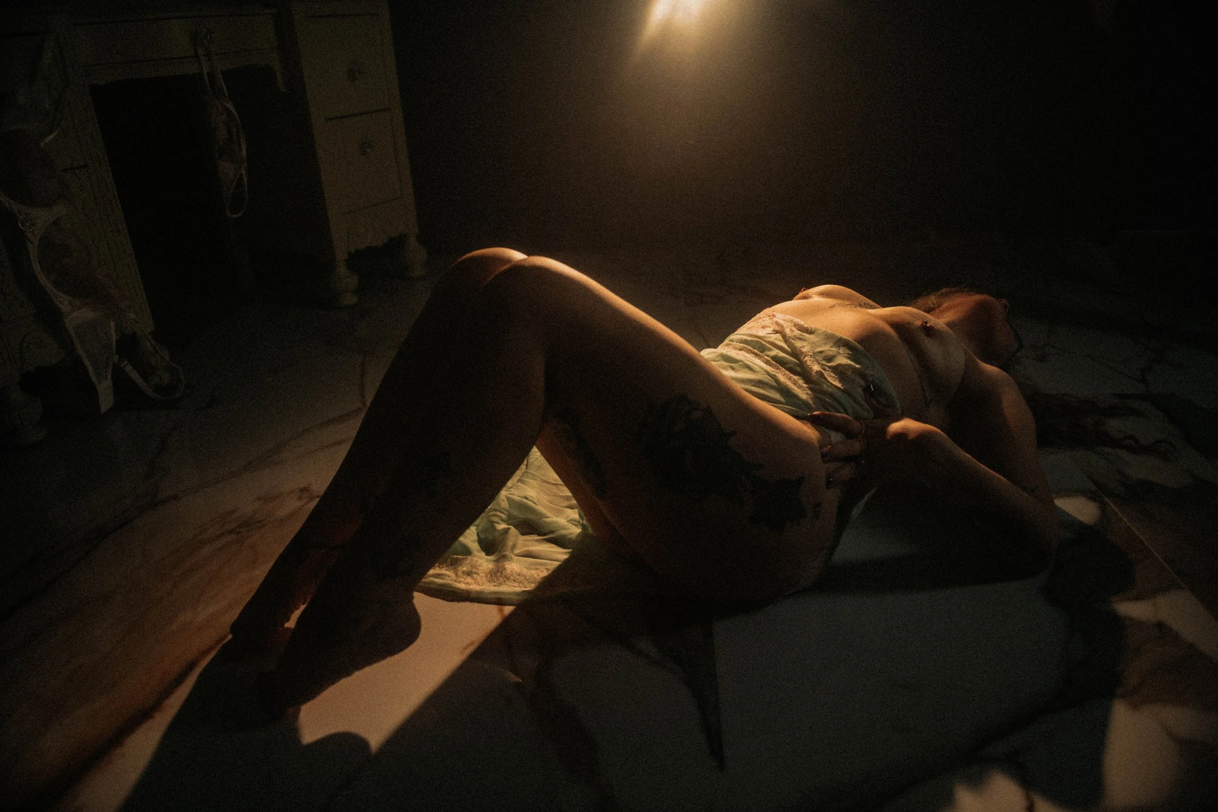 Cinematic boudoir portrait with low light, shadow play, and floor pose in Terre Haute studio