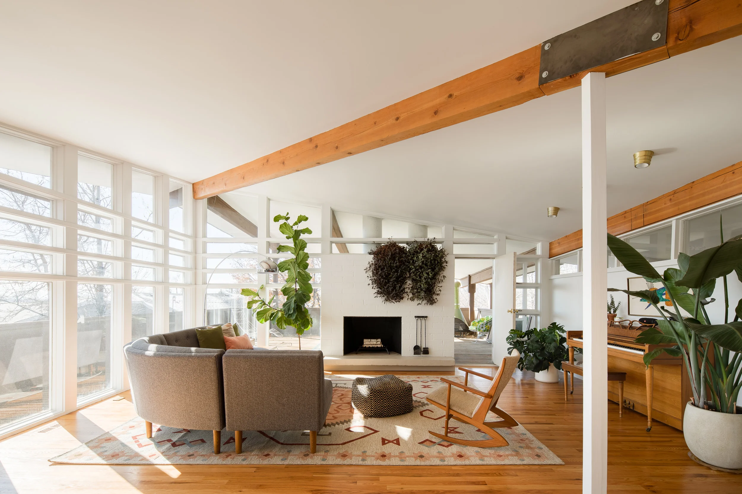 The couple painted the home’s interior walls with Benjamin Moore’s Decorator’s White . A West Elm Retro Rounded sectional couch nestles into the space opposite a Georg Jensen Model 97 Rocking Chair , all atop a Rizzy Home Mesa Rug .