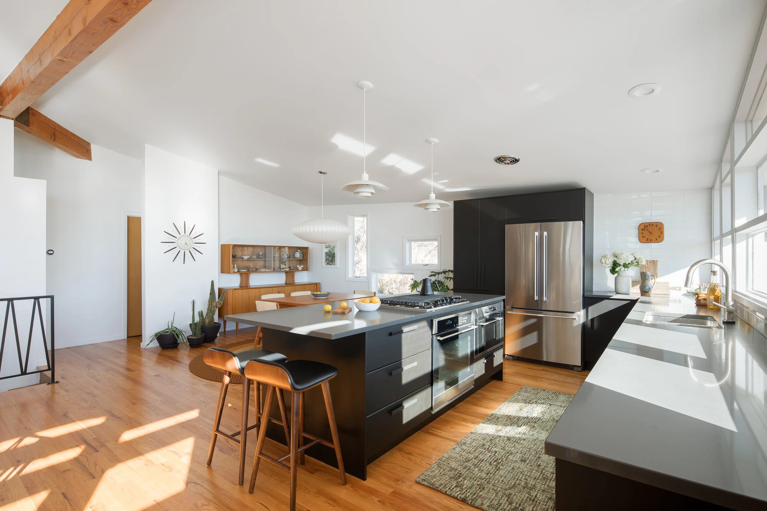 The couple removed a wall to create the open kitchen and dining area. Ikea cabinets form an L-shape around the perimeter. Article Sede barstools line the island and Poul Henningson PH4/3 Lights hang above.