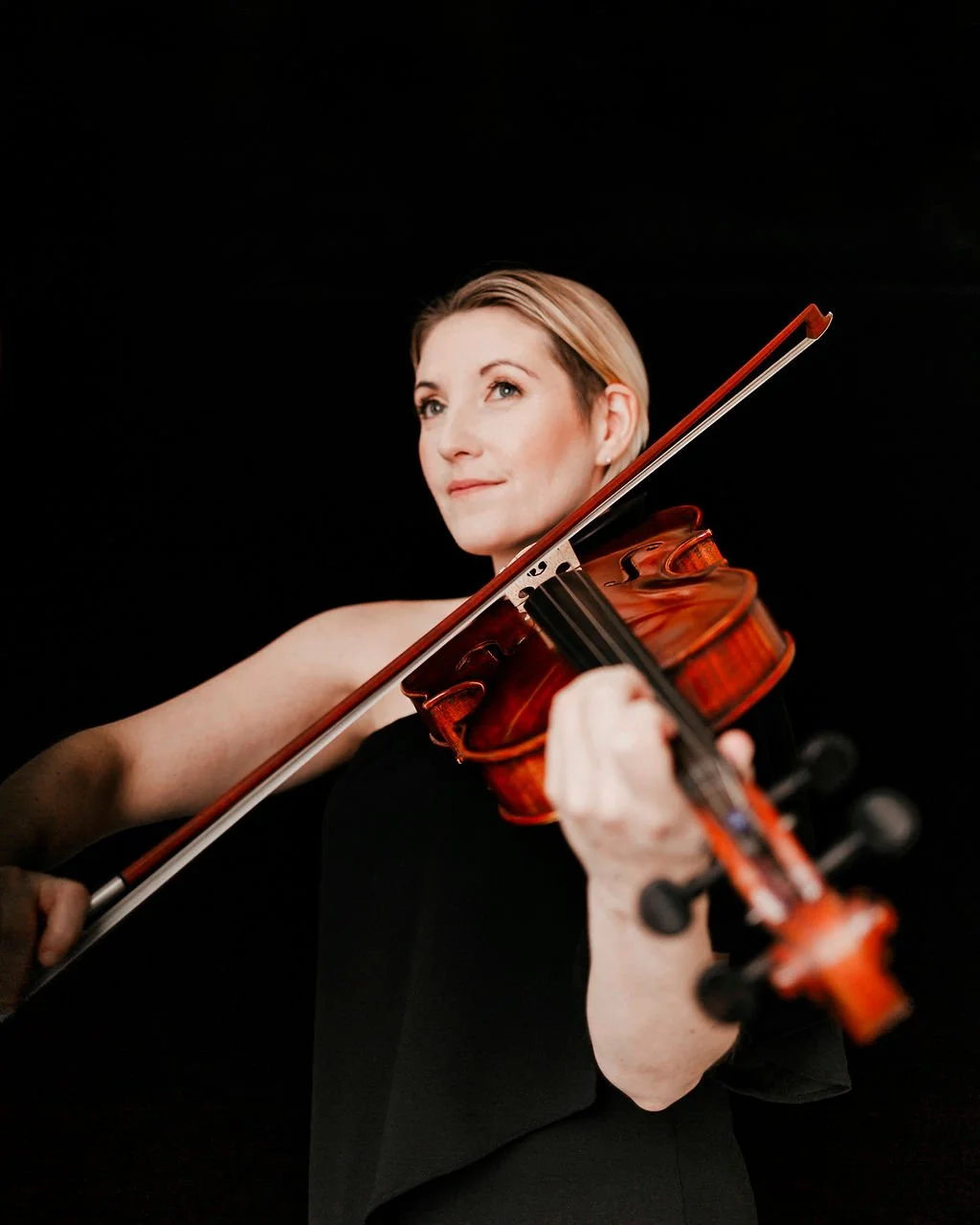 Kimberly Musial, President & Artistic Director of Luminous Sounds. Headshot playing the viola.