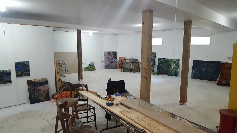 The Artist Cottage work space after artists had packed up all their belongings in 2016. The artwork shown is being stored preparation for an upcoming exhibit. A divider wall is visible at left. This space may not be available in 2019. New studios are being developed.