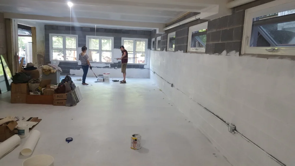 This space is pretty much brand new. This image shows a continuation of the space shown above. Volunteers above paint the space white in preparation for its first use in 2016. An overhead door allows for easy move of large scale items in and out of the studio.