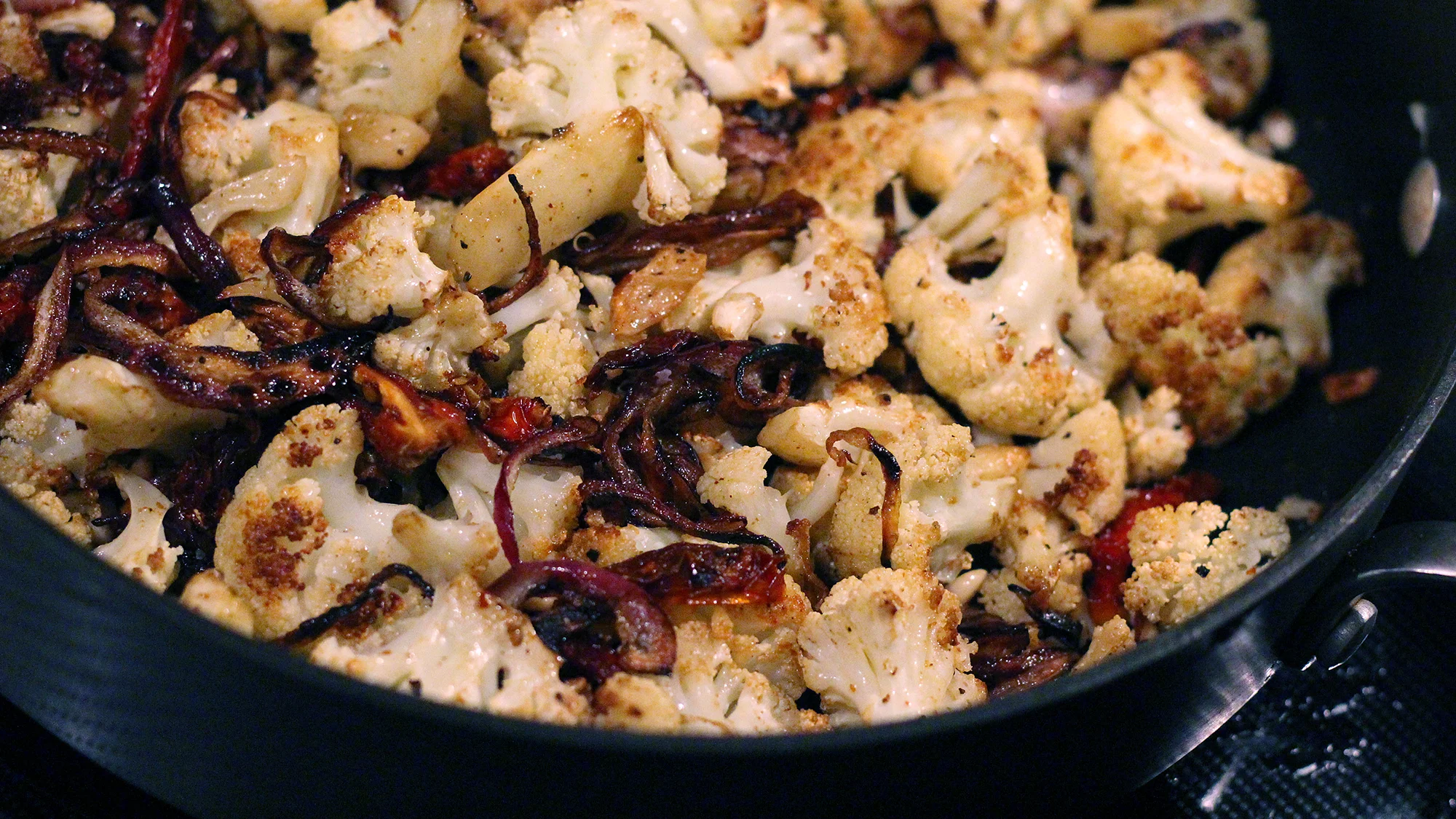 The cauliflower starts in the oven to give it it's crispy, delicious taste, but it's finished in a sauté of the caramelized onions, sun-dried tomatoes, lemon juice and, eventually, arugula.