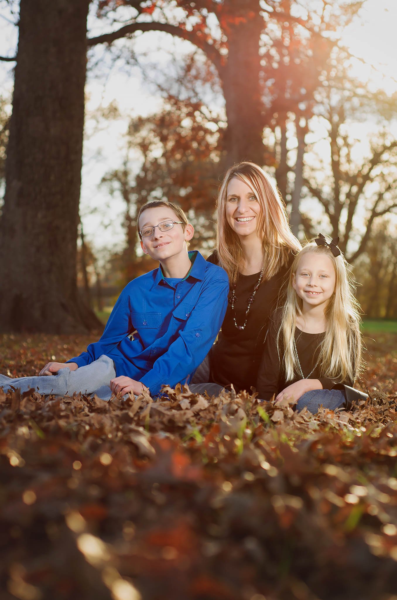 family-of-three-sitting-in-fall-leaves.jpg