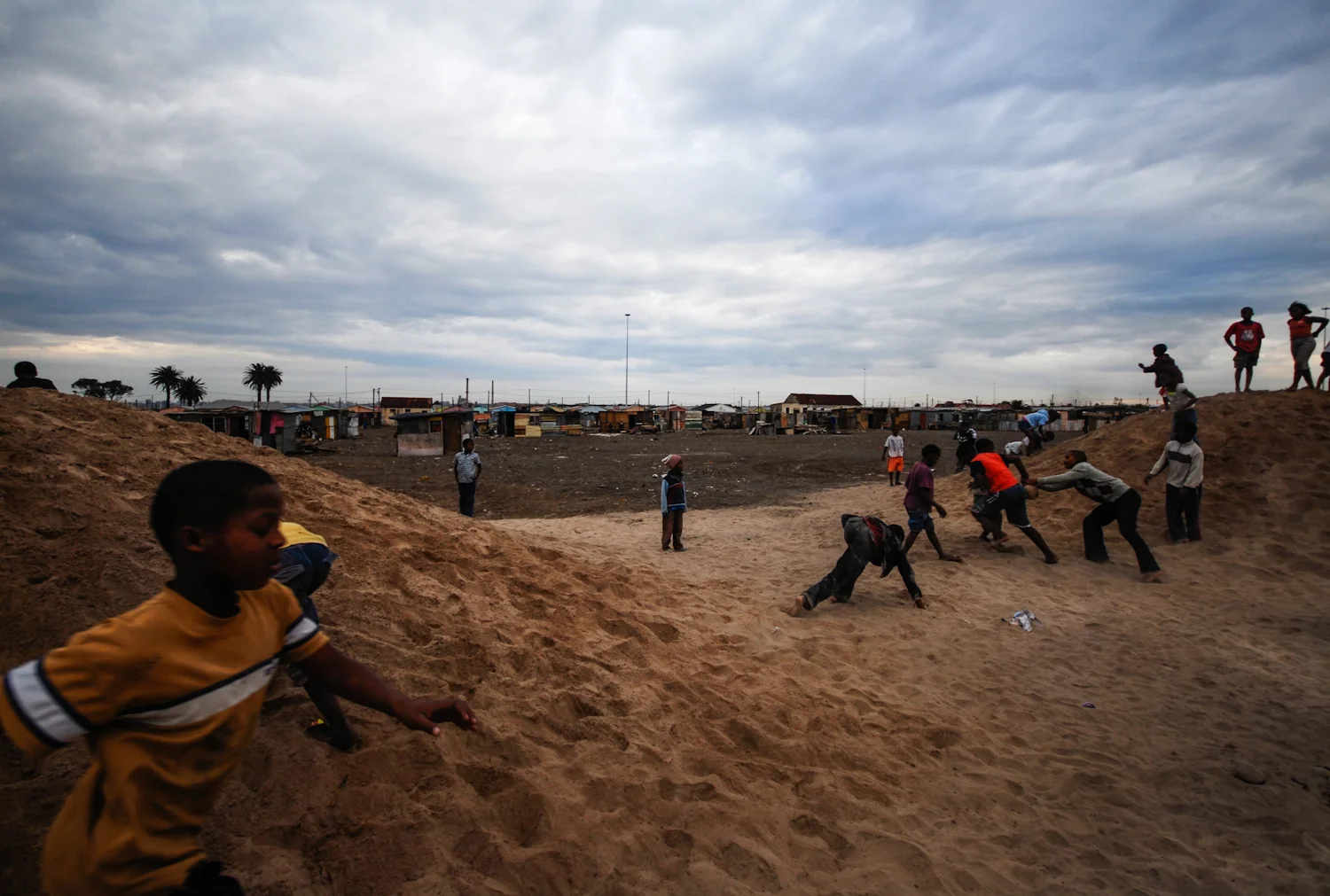 Children play on piles of sand used for constructing the nearby library