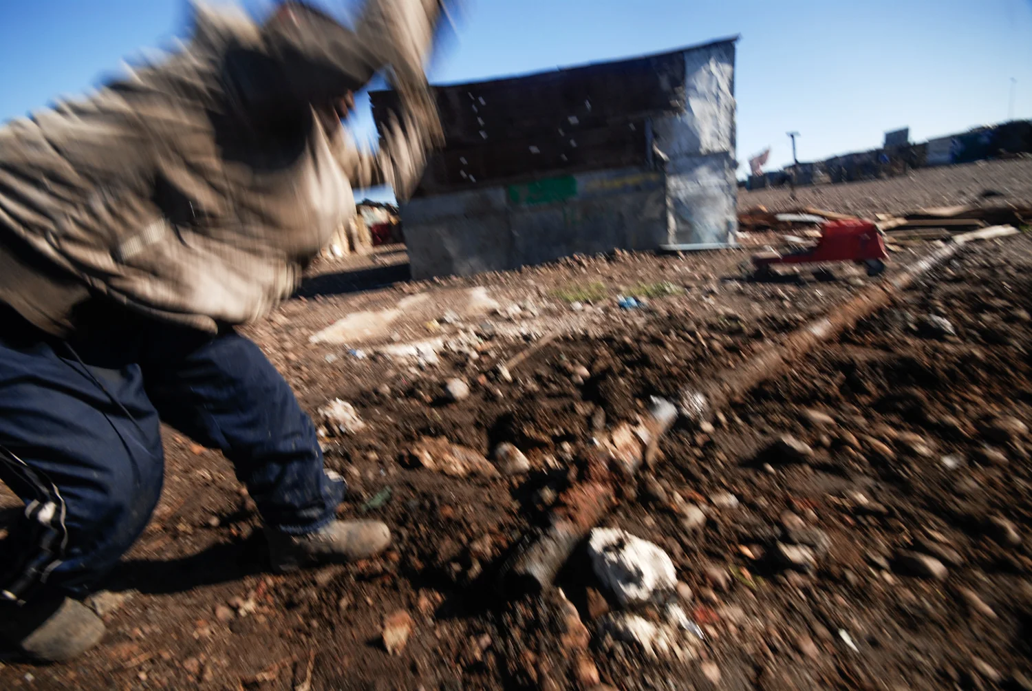A resident uses a large stone to break old copper pipes so that he can sell them