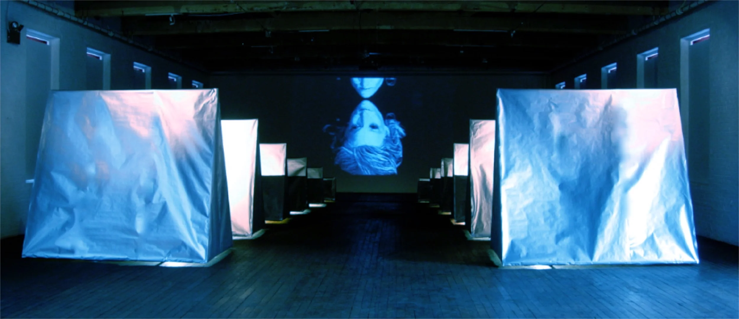 Land of the Lost , 2008, mixed media and video/sound installation, 12‘ x 60‘ x 100’ A formation of “tent” sculptures appear to be floating on light -- the video shows an ascent up to and above the tree line in the Swiss Alps, and people floating in space -- the sound of bells plays throughout the video.