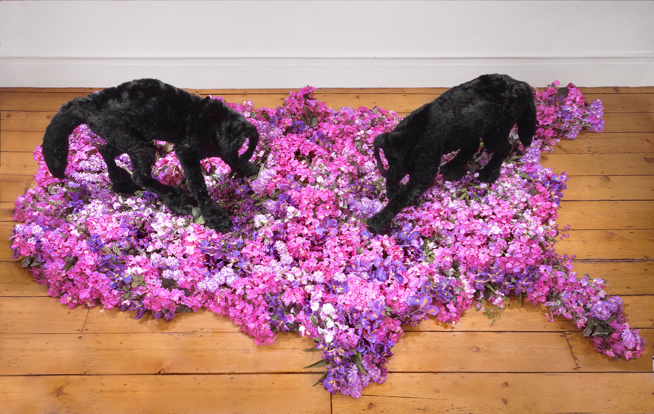 Divine Creatures , 2005, acrylic, wood, polyester, silk flowers, polymer, audio speakers, sound, 3’ x 16’ x 10’ Headless creatures prowl a funereal map of the United States. A remix of Robert Johnson's Hellhound on My Trail plays from hidden audio speakers. The creatures' mirrored necks produce an unexpected trompe of negative space.