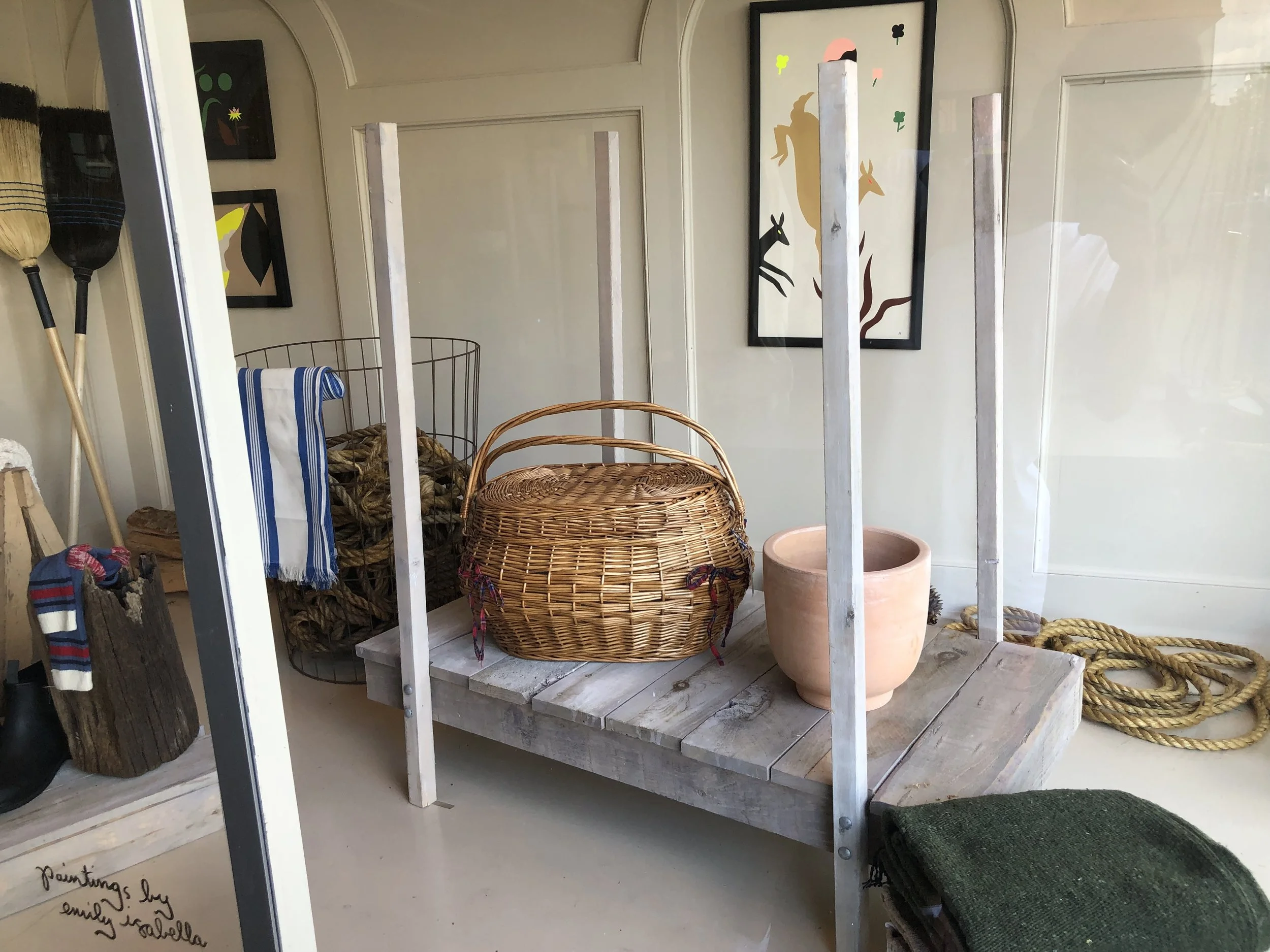 Display window showcasing woven baskets, ropes, and a terracotta pot inside a home decor store.